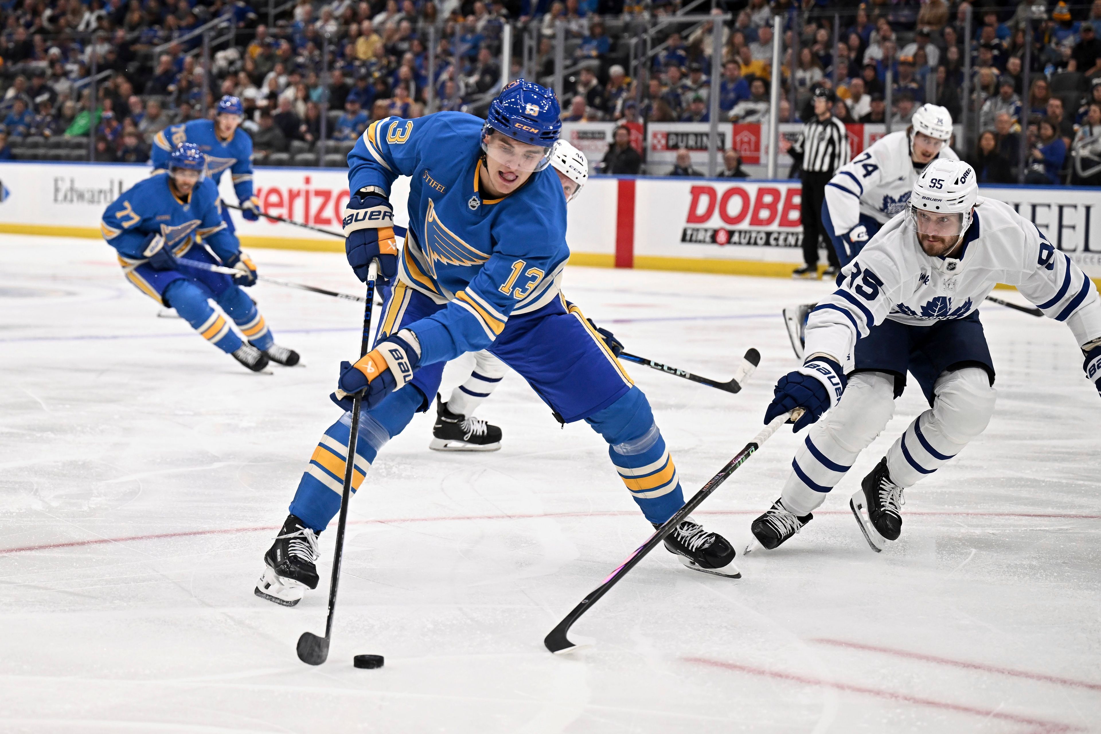 St. Louis Blues' Alexey Toropchenko (13) controls the puck as Toronto Maple Leafs' Olver Ekman-Larsson (95) defends during the second period of an NHL hockey game Saturday, Nov. 2, 2024, in St. Louis. (AP Photo/Connor Hamilton)