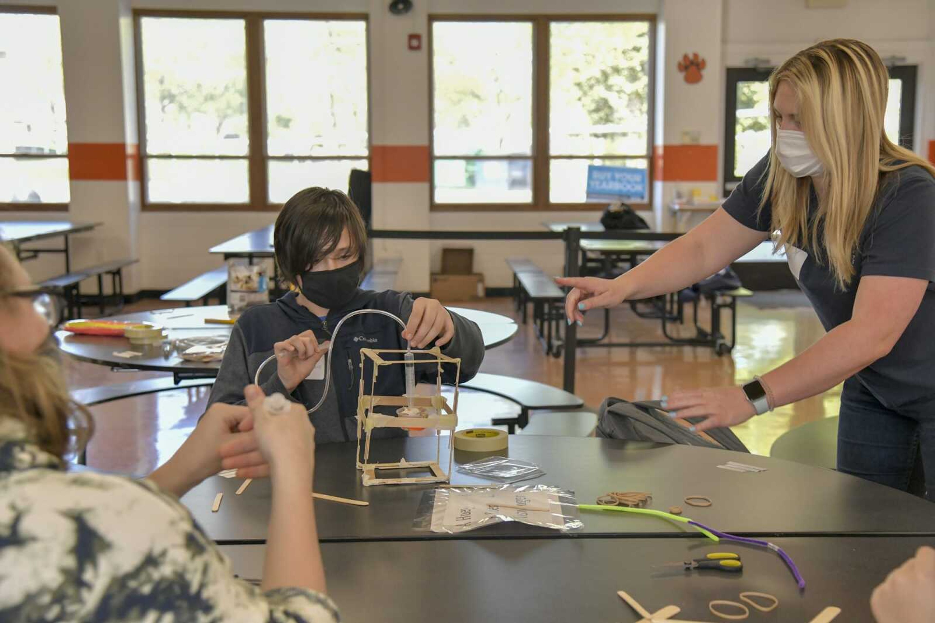 Packaging engineer Rachel Reifsteck, right, observes as Noah Caldwell, 13, tests the equalizing air pressure system on their group project at Central Junior High School in Cape Girardeau on Thursday.