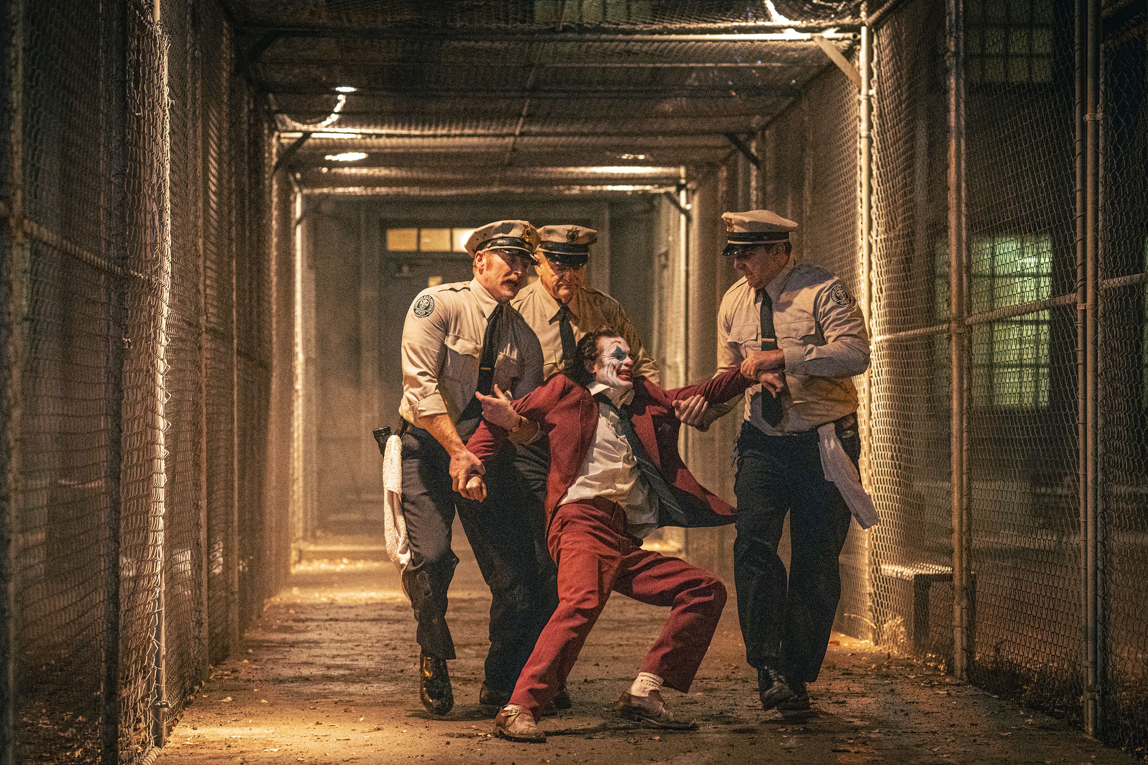 This image released by Warner Bros. Pictures shows Joaquin Phoenix, foreground center, and Brendan Gleeson, background center, in a scene from "Joker: Folie à Deux." (Niko Tavernise/Warner Bros. Pictures via AP)