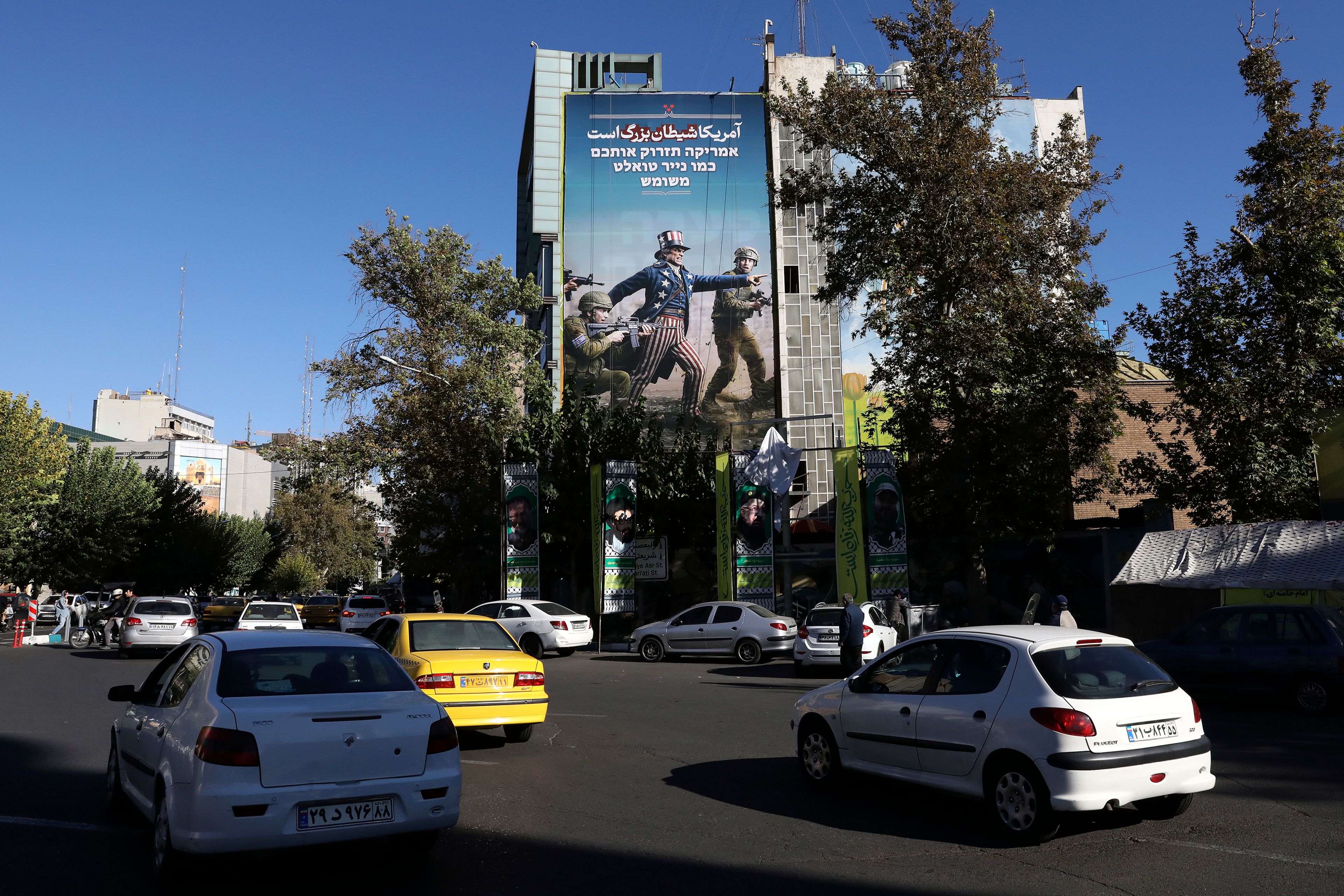 Vehicles drive past an anti-U.S. and anti-Israel banner with writing in Farsi reading: "America is the great Satan", and in Hebrew "America will throw you away like used toilet paper", at the Felestin (Palestine) Sq. in downtown Tehran, Iran, Wednesday, Nov. 6, 2024. (AP Photo/Vahid Salemi)