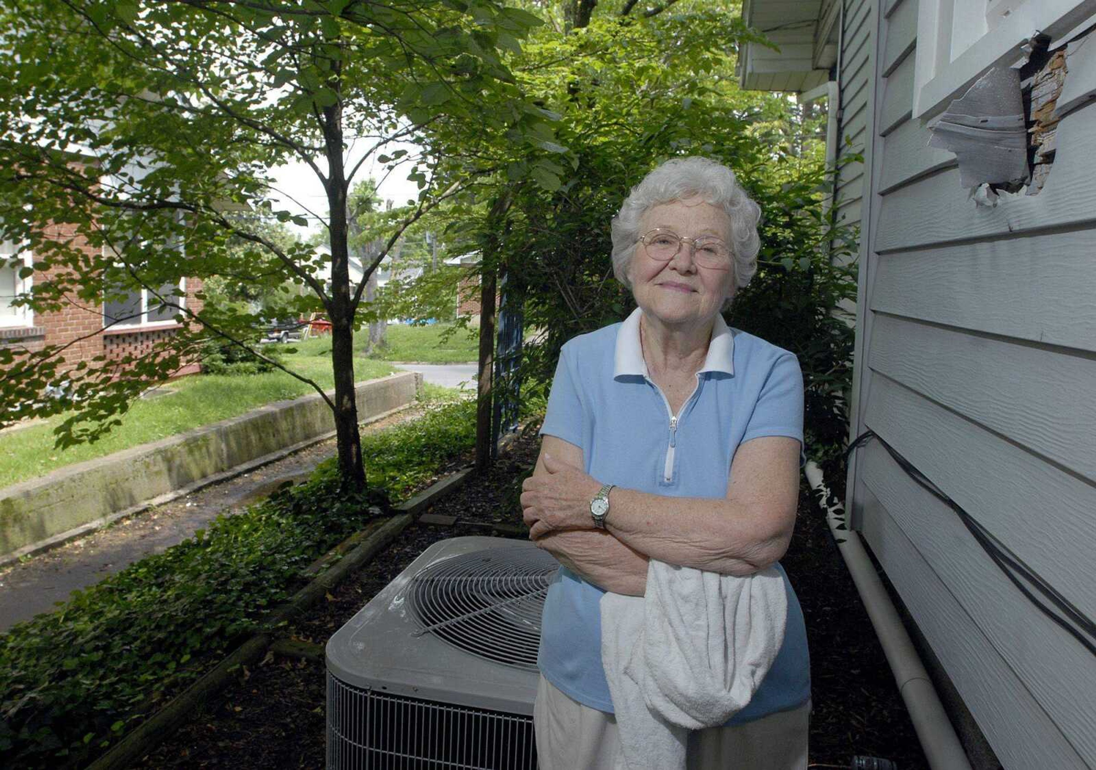 Millie Strom stands next to her Dunklin Street house Tuesday in Cape Girardeau. An unknown person used an ax to put a large hole in the house when she was out of town last summer. Strom has to stuff a towel in the hole to keep birds from building nests there. (Laura Simon)