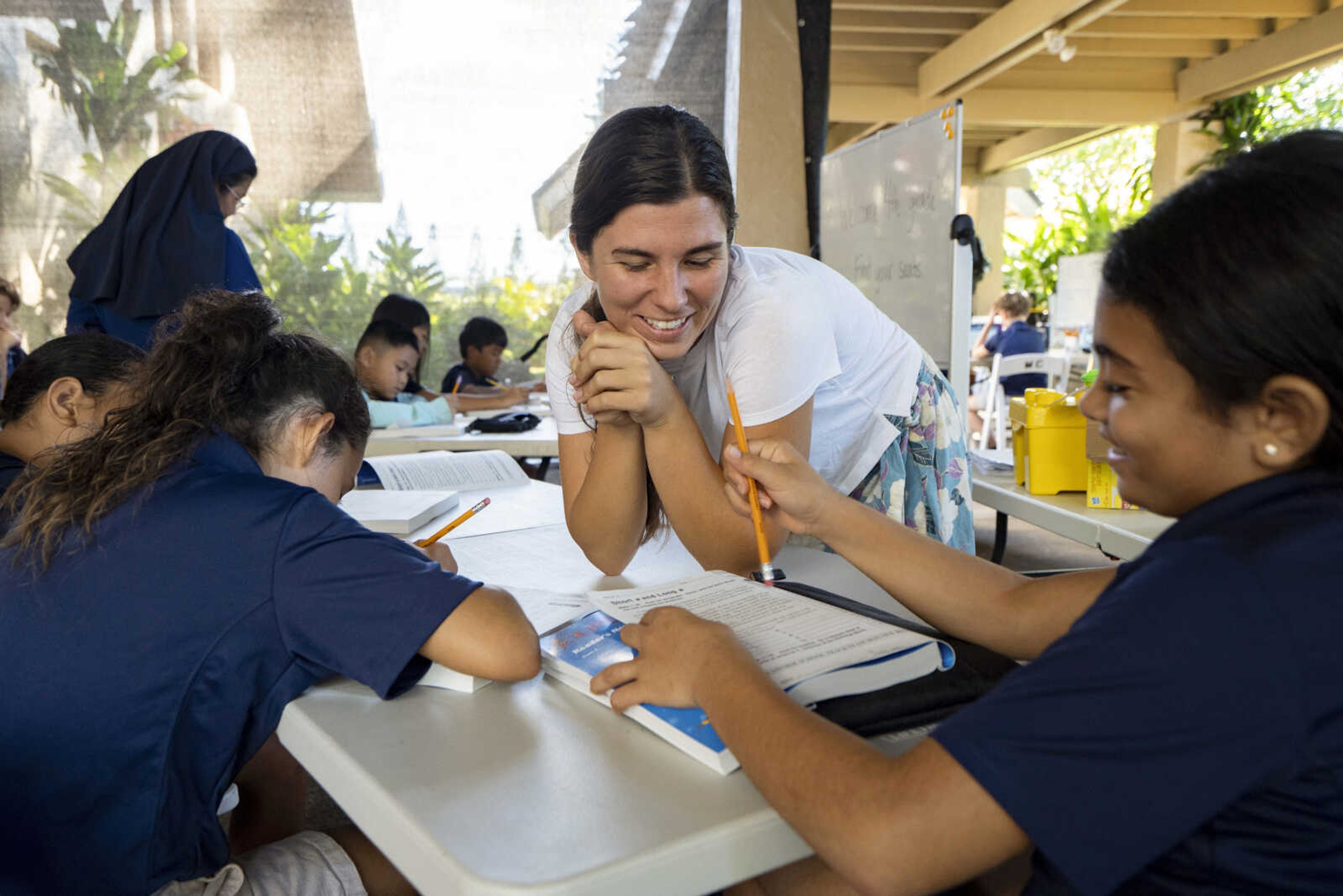 Sacred Hearts School second grade teacher Courtney Copriviza interacts with the fourth graders at their temporary school site at Sacred Hearts Mission Church on Oct. 3 in Lahaina, Hawaii. Sacred Hearts and other private schools across the state took in displaced public school students, and offered a year of free tuition.