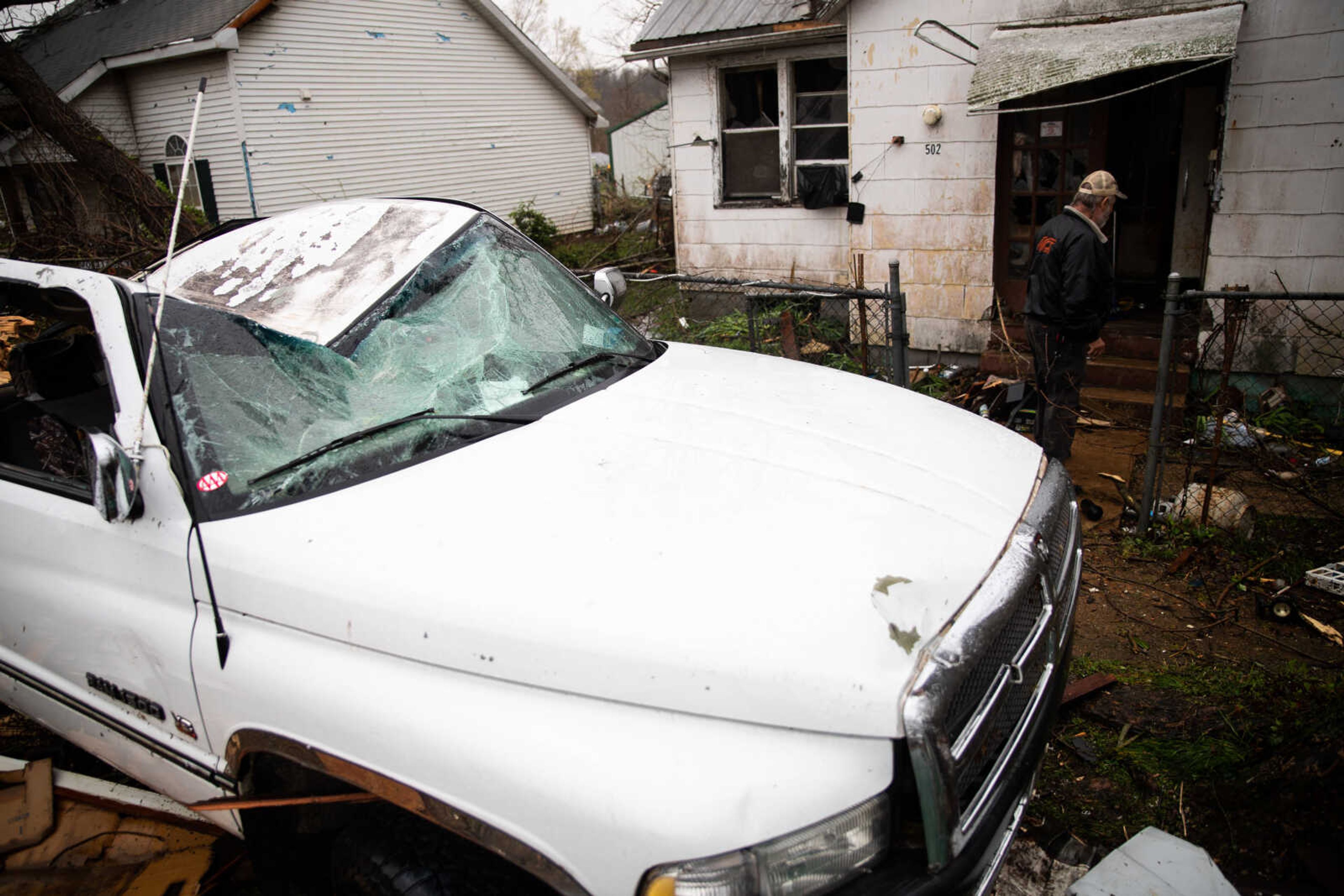 John Seabaugh walks into his house past his truck which was heavily damaged by debris from the tornado.