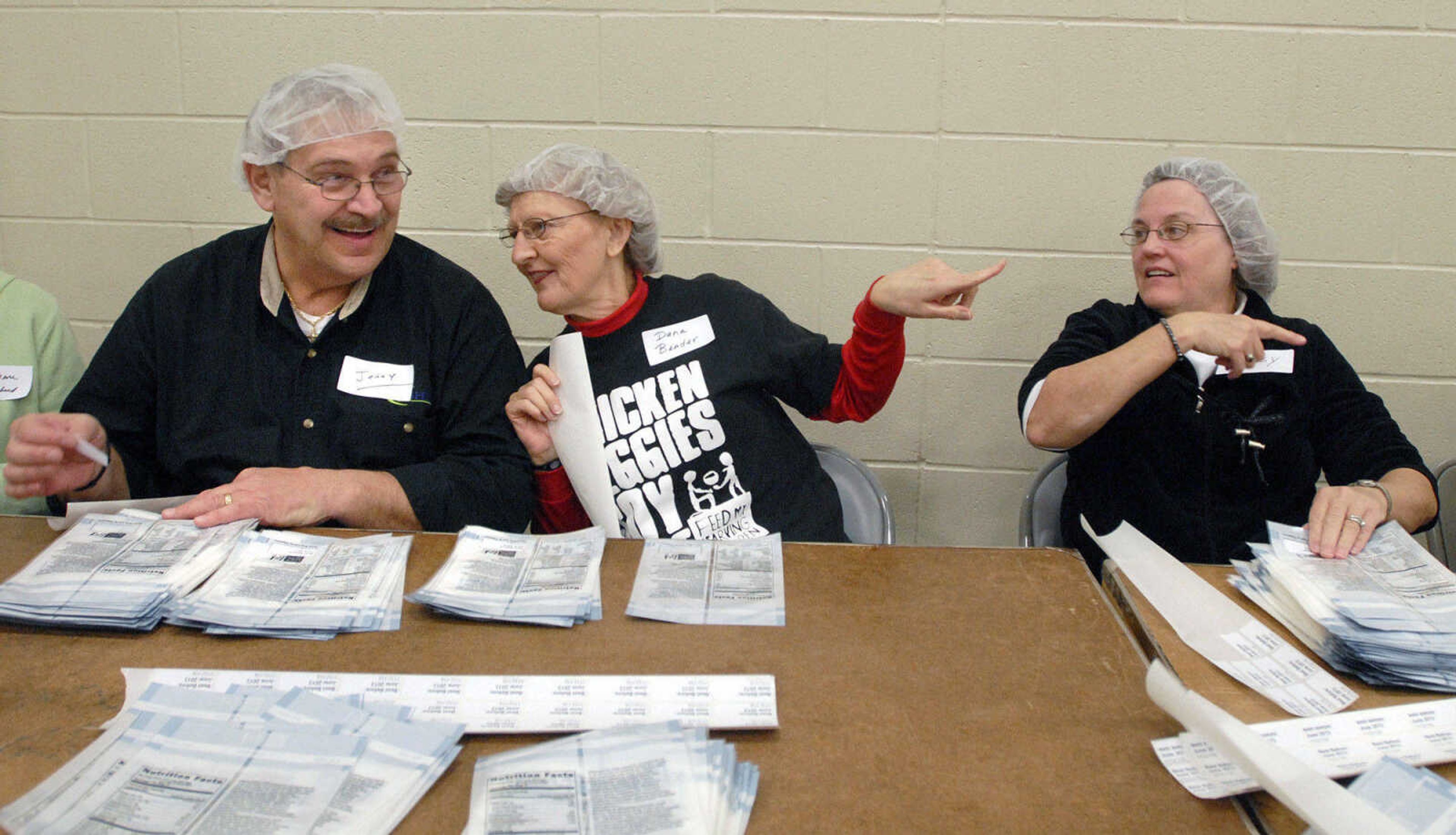 LAURA SIMON ~ lsimon@semissourian.com
Jerry and Dana Bender and Missy Ferguson chat while applying the expiration dates to each MannaPack Rice bags Friday night, Dec. 9, 2011 during the Feed My Starving Children Mobilepack event at Shawnee Park center in Cape Girardeau.