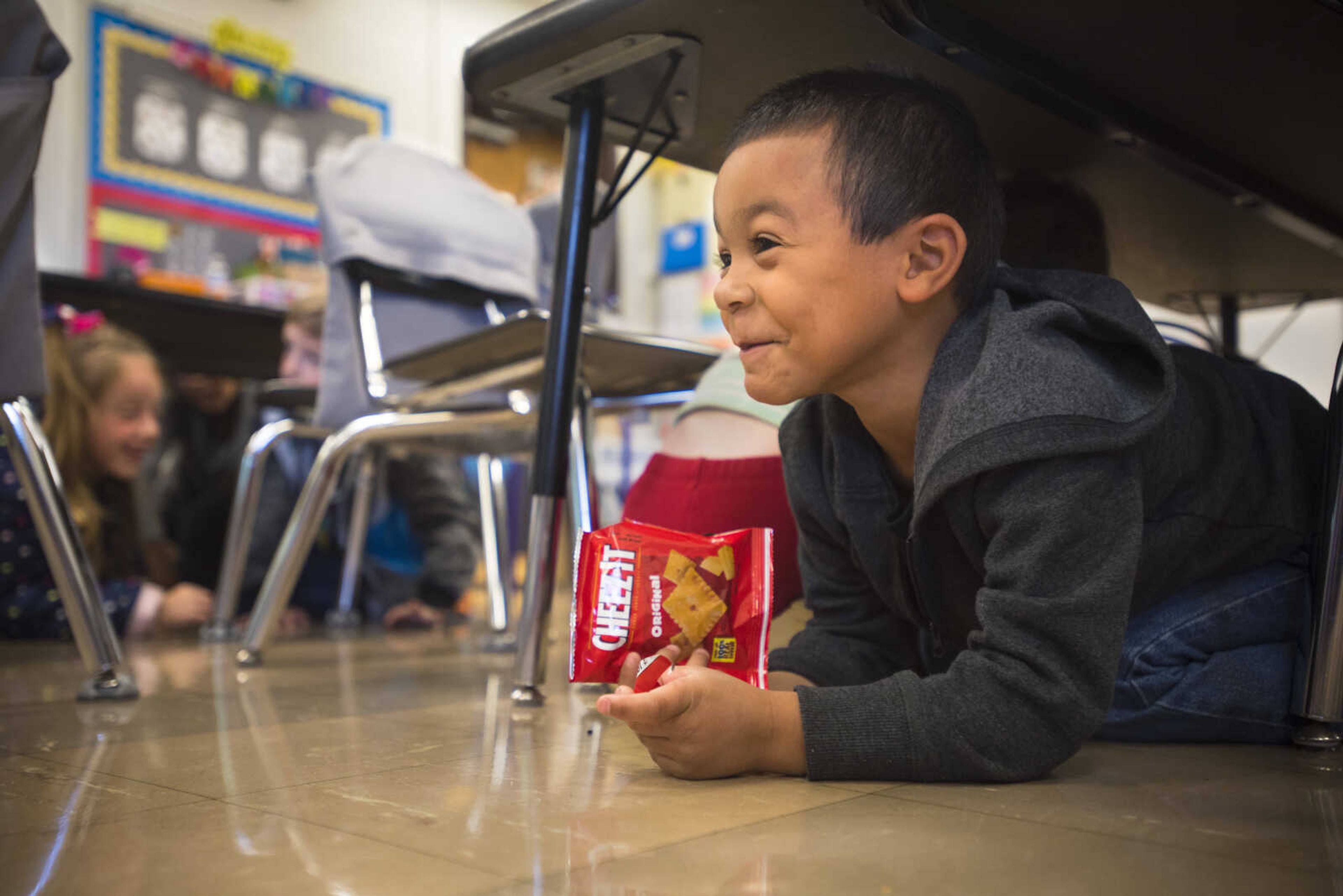 Alma Schrader kindergarten student Logan Franklin, right, smiles while emerging from cover during an International ShakeOut Day earthquake drill on Thursday, Oct. 18, 2018, in Cape Girardeau. The drill was conducted at 10:18 a.m. as part of the Great ShakeOut, an annual earthquake preparedness drill held at schools and organizations across the country to practice earthquake safety.