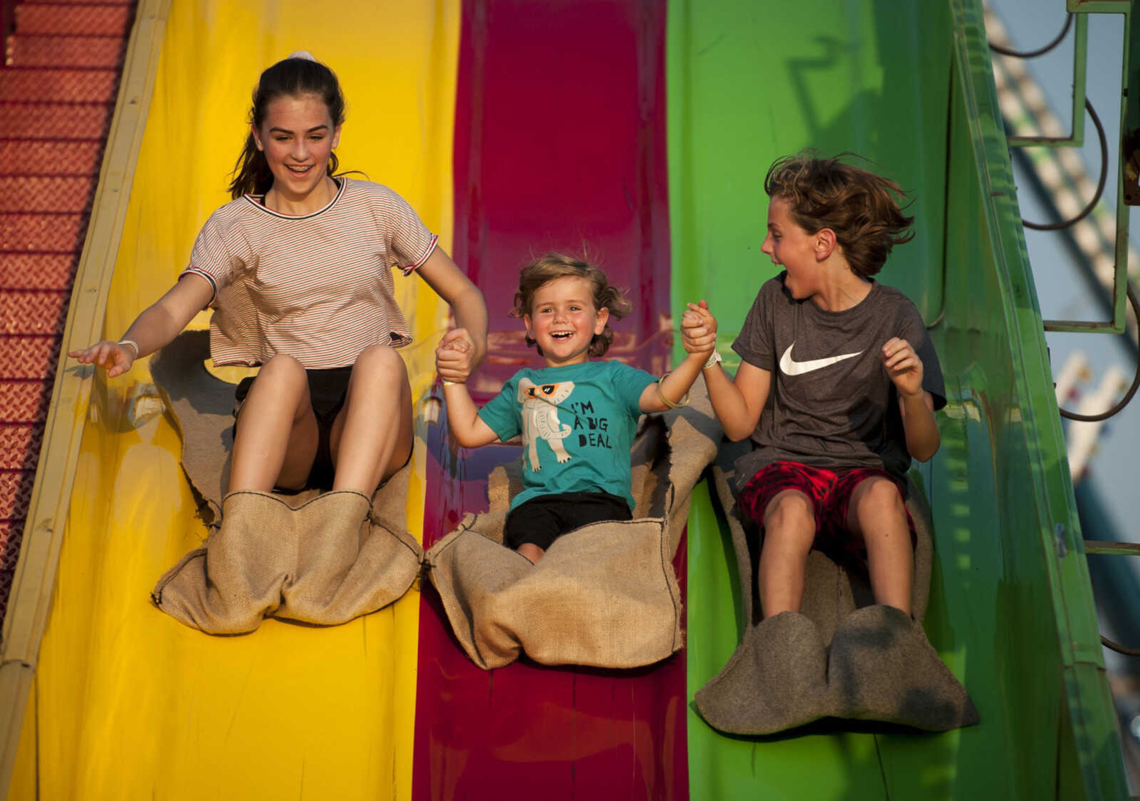 Aralia Brune, 14, far left, slides with her brothers Harrison, 3, and Ellis, 11, while holding hands Sept. 9, 2019, at the SEMO District Fair in Cape Girardeau.