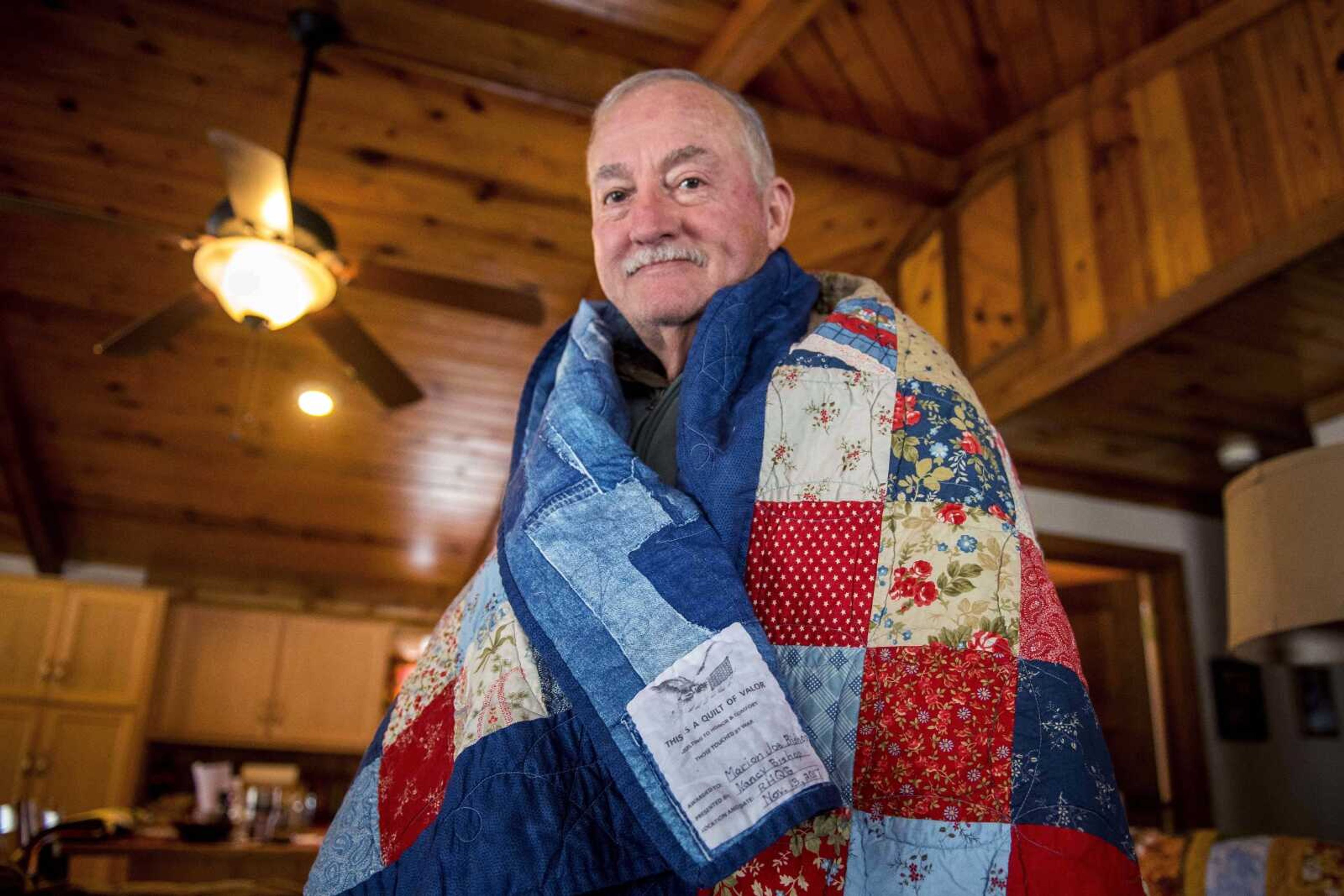 Navy veteran Joe Bishop poses with a Quilt of Valor his wife, Nancy, made for him in his home Thursday, Nov. 15, 2018.