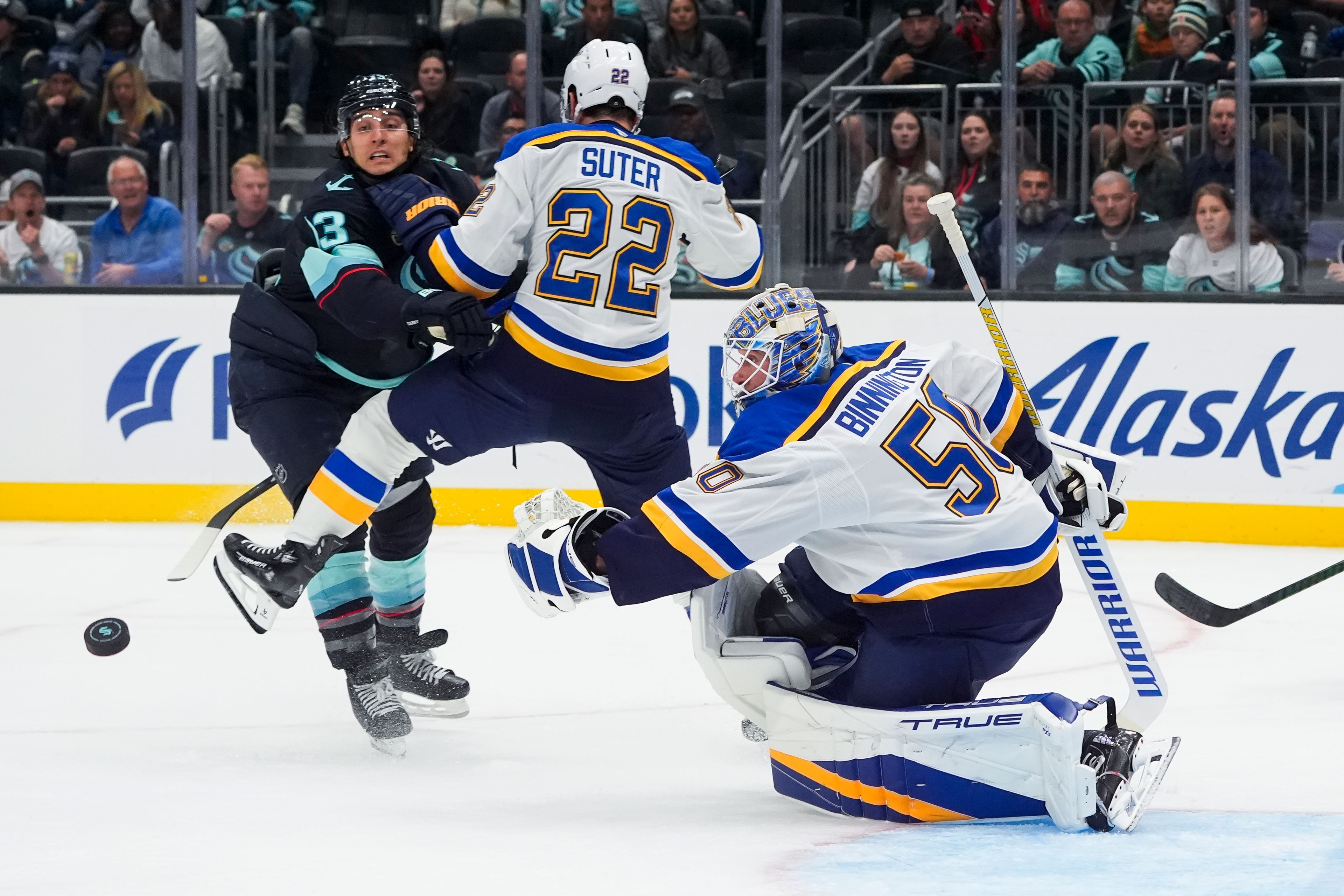 St. Louis Blues goaltender Jordan Binnington (50) looks on as the puck flies out of reach and defenseman Ryan Suter (22) and Seattle Kraken left wing Brandon Tanev, left, collide during the second period of an NHL hockey game Tuesday, Oct. 8, 2024, in Seattle. (AP Photo/Lindsey Wasson)