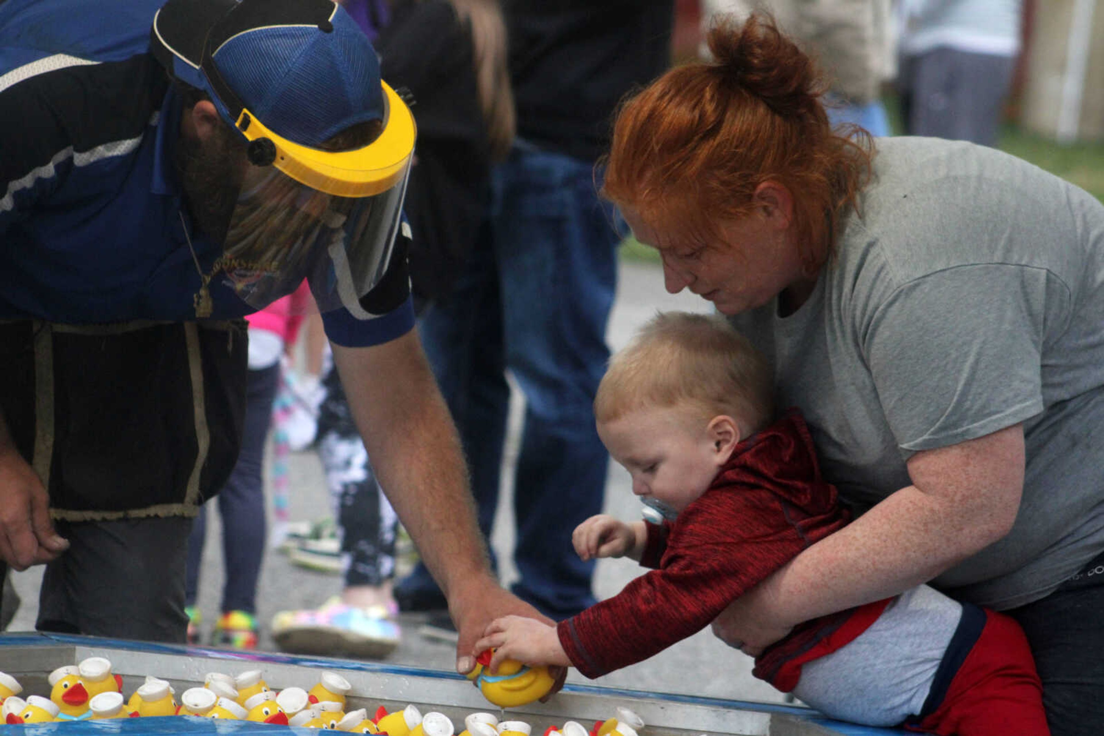 Amber Whittington, right, helps her son, Emmett, 2, select a rubber duck in one of many games offered at Scott City Summerfest on Friday, May 28, at Scott City Park in Scott City.