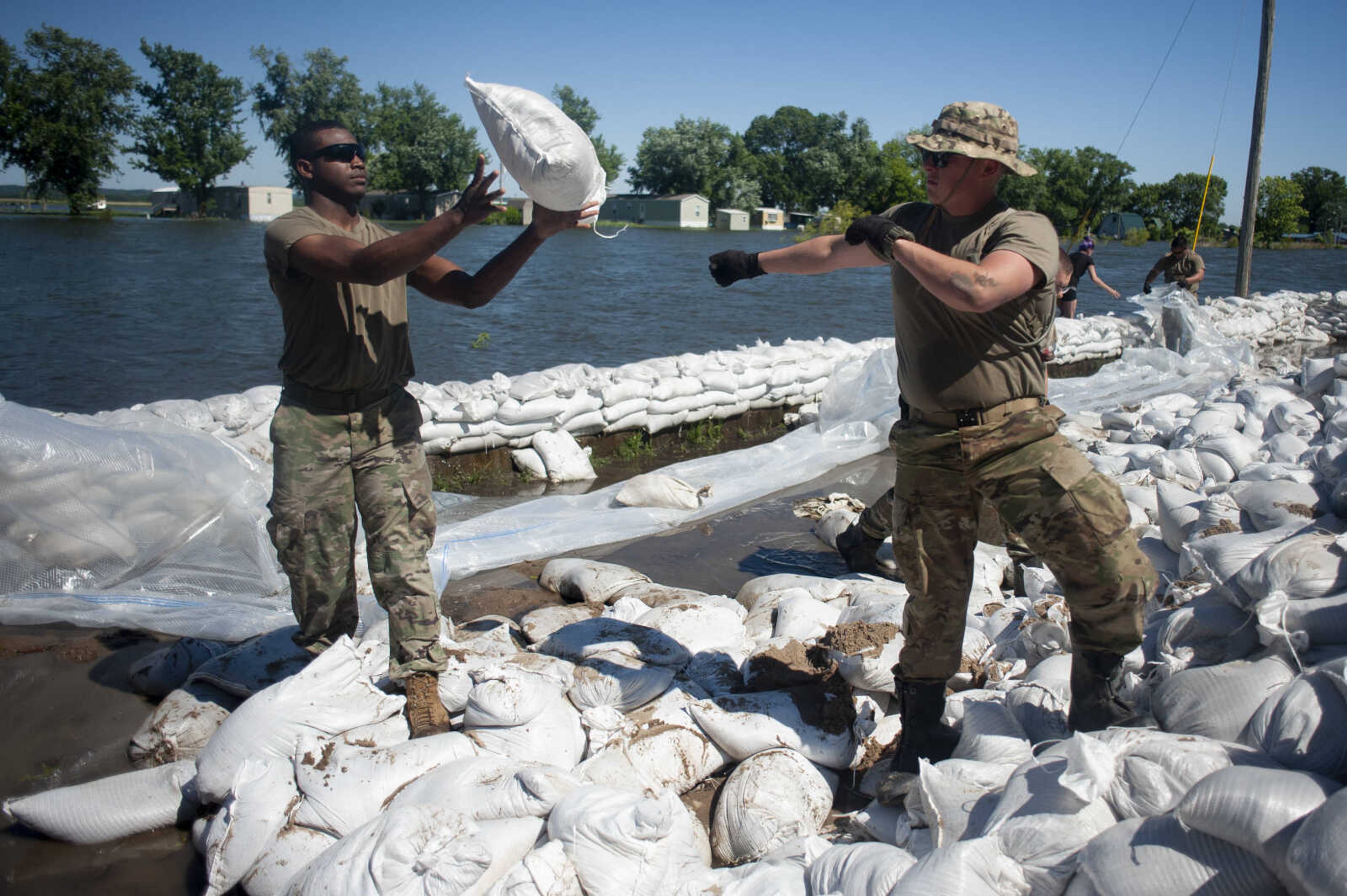 Illinois National Guard member Michael Sheppard, right, and fellow Guard member Antione Gully, left, help build up existing sandbag barriers to hold back floodwaters Monday, June 10, 2019, along Brookwood Drive in East Cape Girardeau, Illinois.