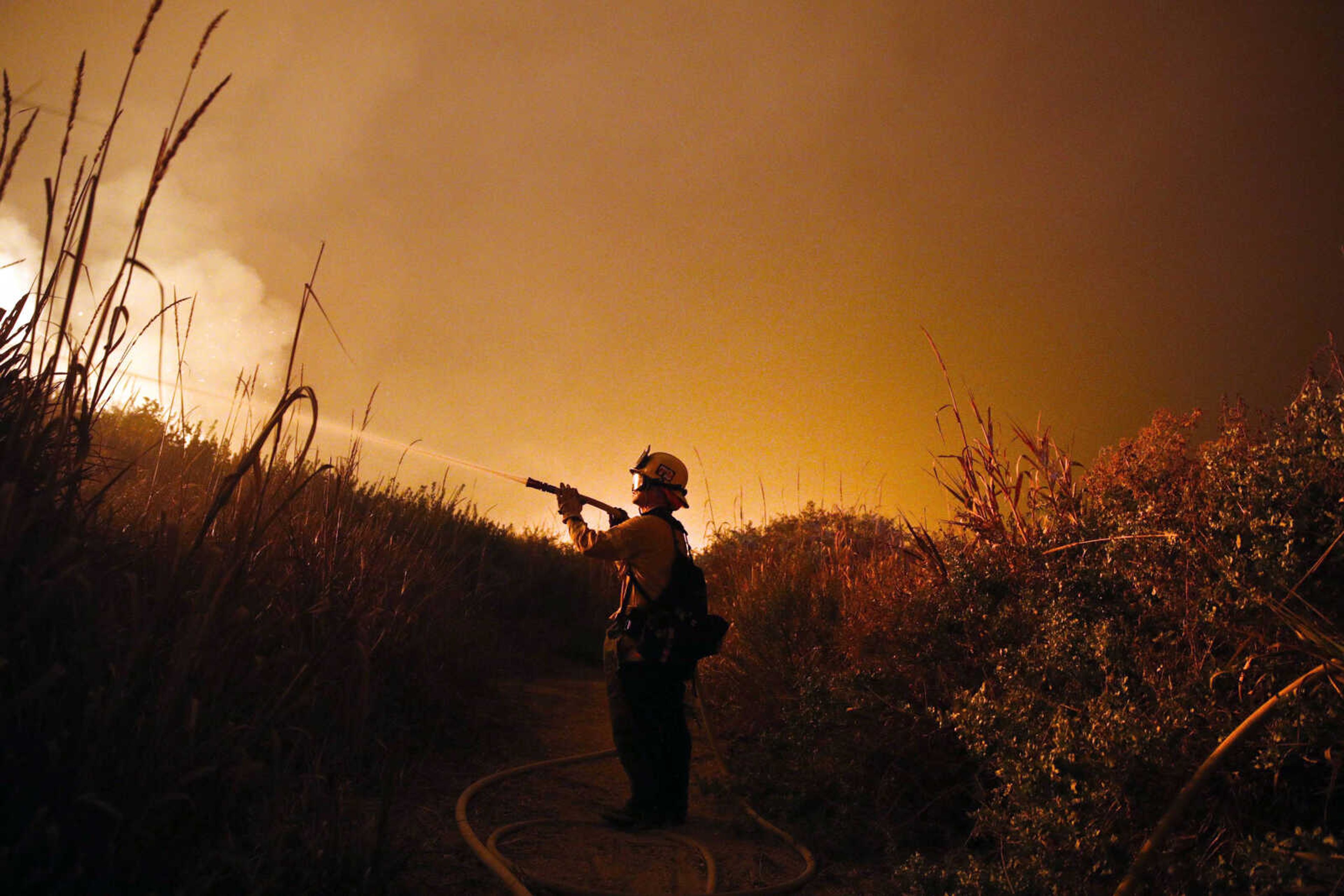 Firefighter Ryan Spencer battles a wildfire as it burns along a hillside toward homes Dec. 7 in La Conchita, California.