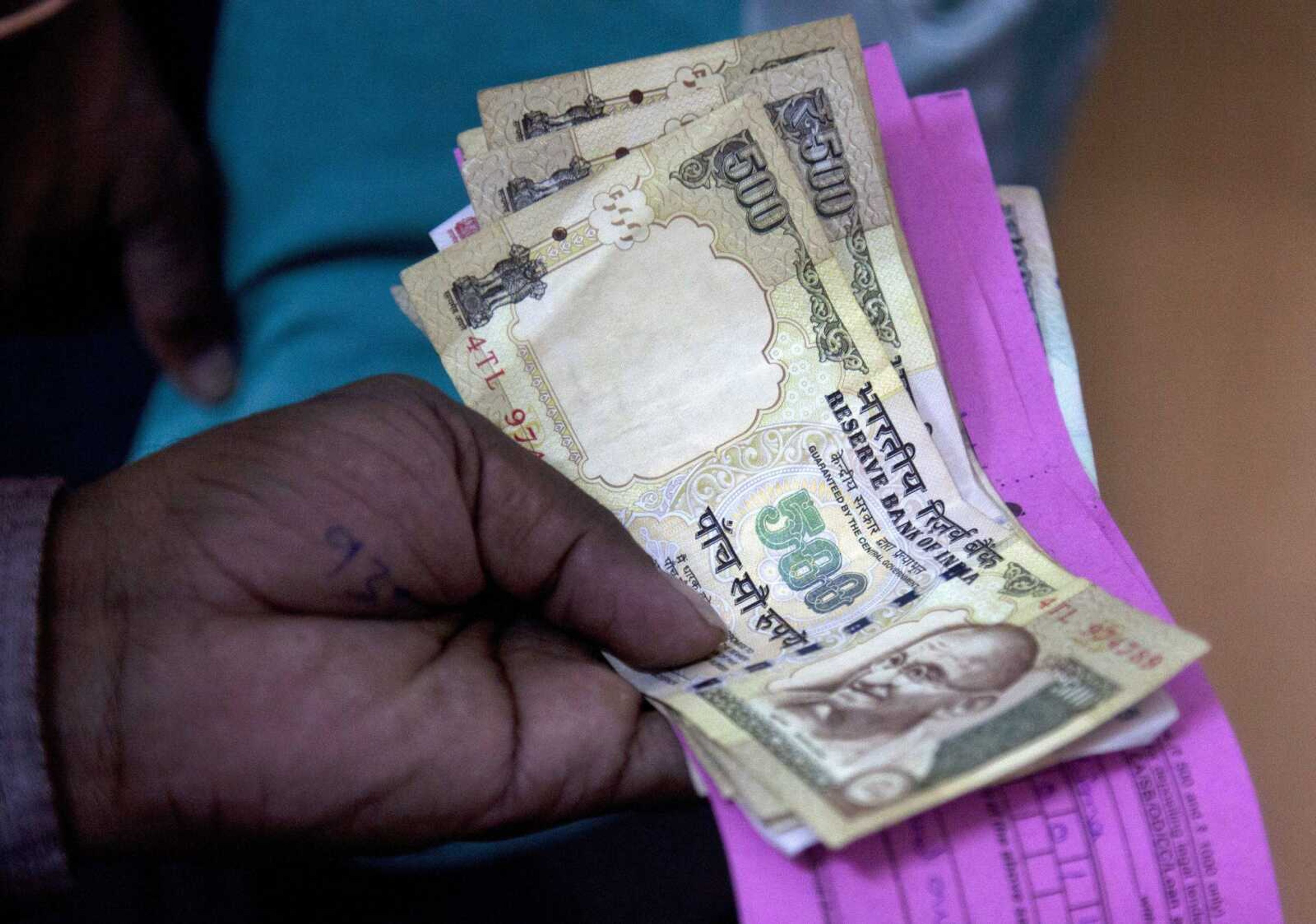 A person on Thursday gives discontinued currency notes for deposit in a bank in Hyderabad. India yanked most of its currency bills from circulation without warning, delivering a jolt to the country's high-performing economy and leaving countless citizens scrambling for cash.