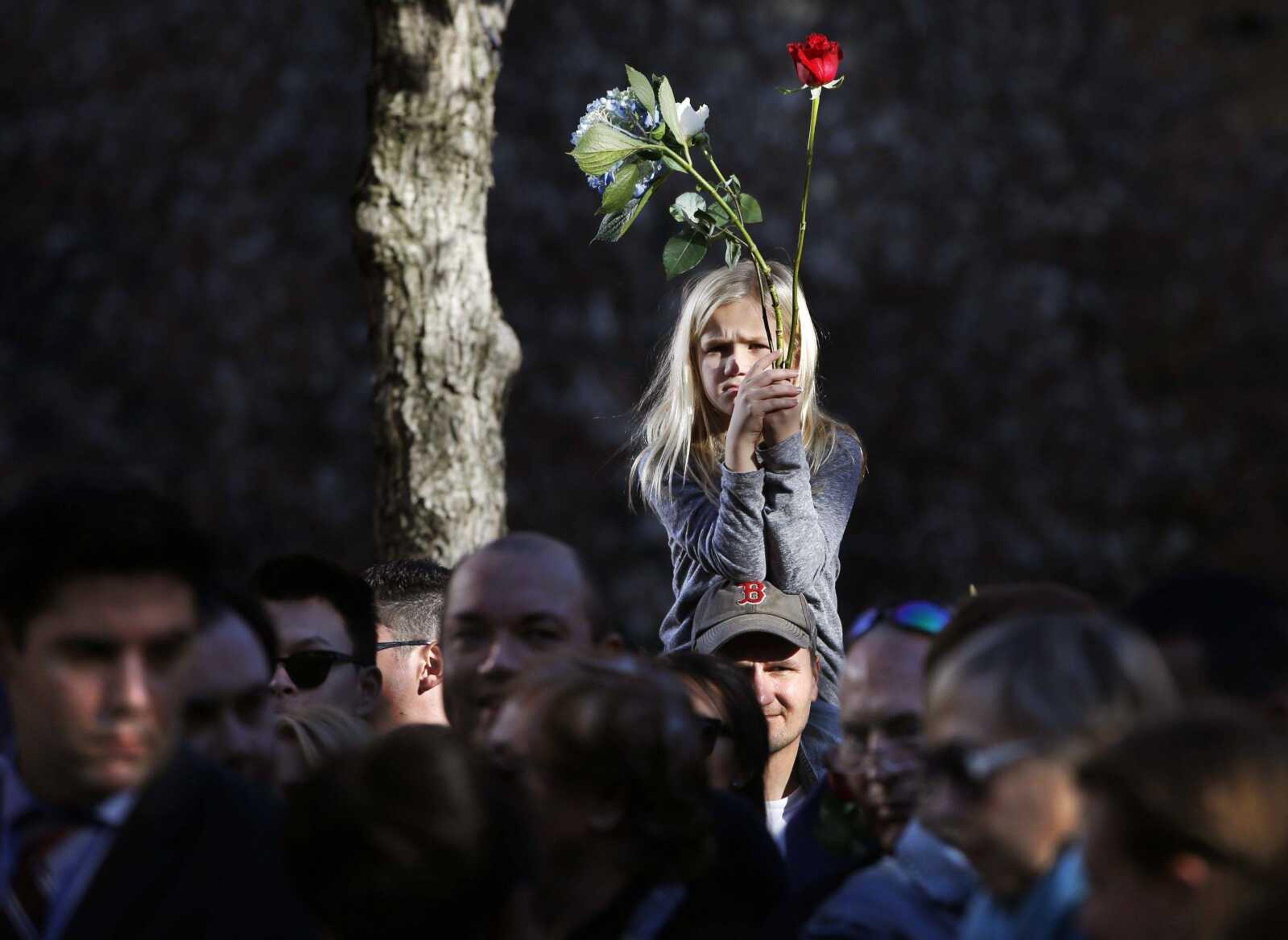 A child sits on her father's shoulders Monday during a ceremony honoring victims of the Paris terrorist attacks at the 9/11 Memorial and Survivor Tree in New York. (Kathy Willens ~ Associated Press)