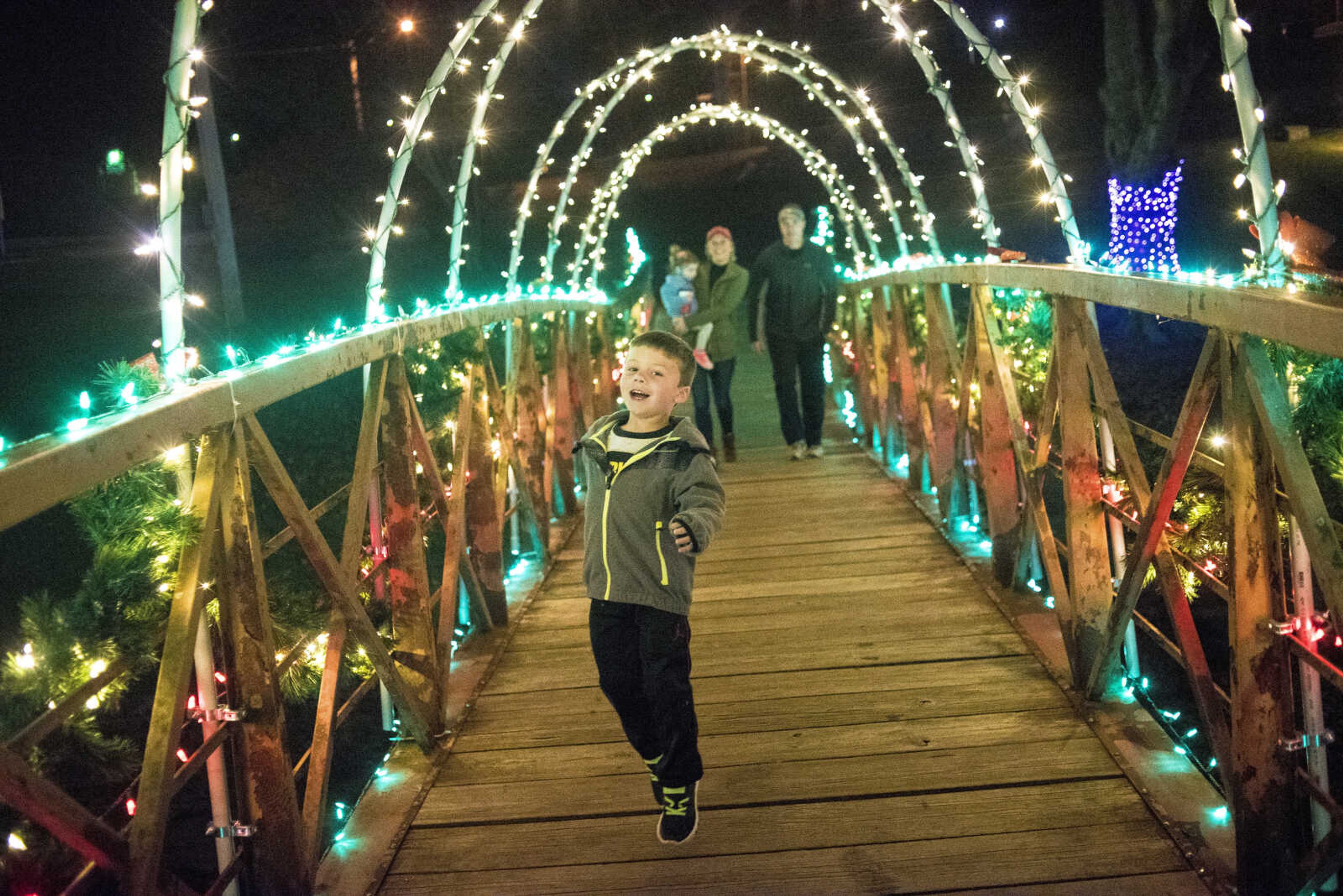 People walk the footbridge during the Jackson Holiday Extravaganza Friday, Nov. 24, 2017 at the Jackson City Park.