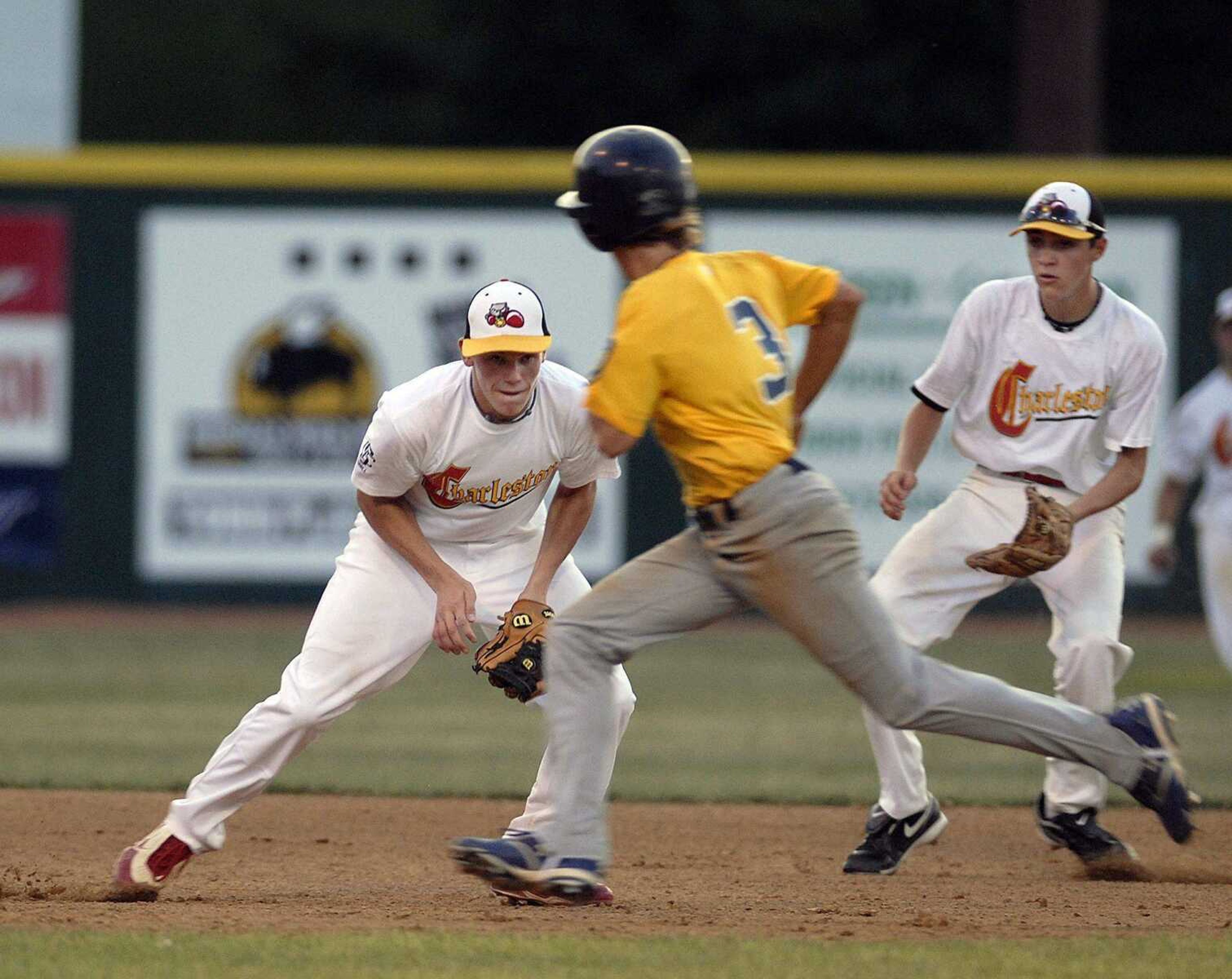 Charleston third baseman Tyler Whybark, left, fields a ball and throws to first as Cape's Skylar Cobb advances to third during the fifth inning Monday at Capaha Park. (Elizabeth Dodd)