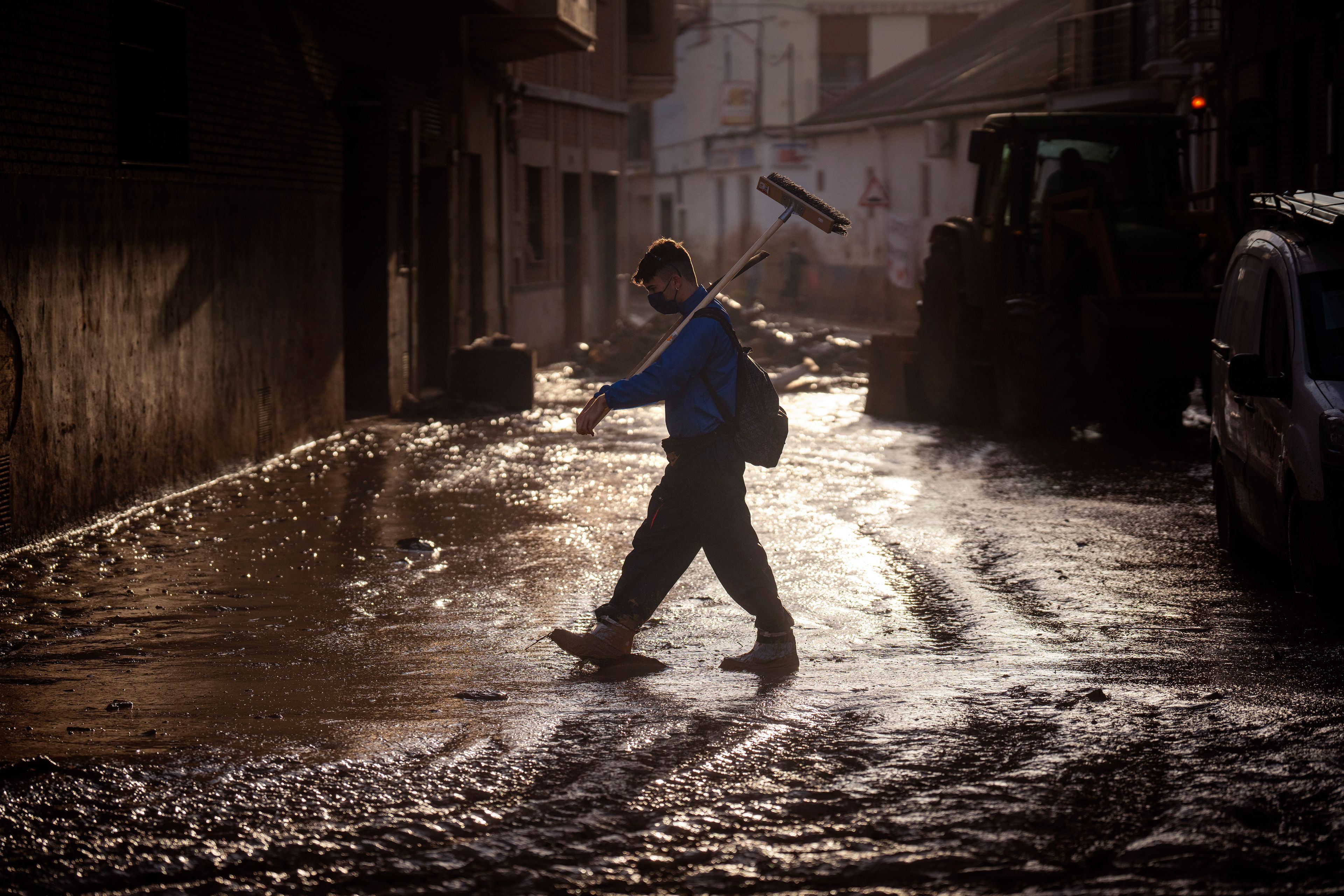 A volunteer walks with a broom over a muddy street in Massanassa, Valencia, Spain, Friday, Nov. 8, 2024. (AP Photo/Emilio Morenatti)