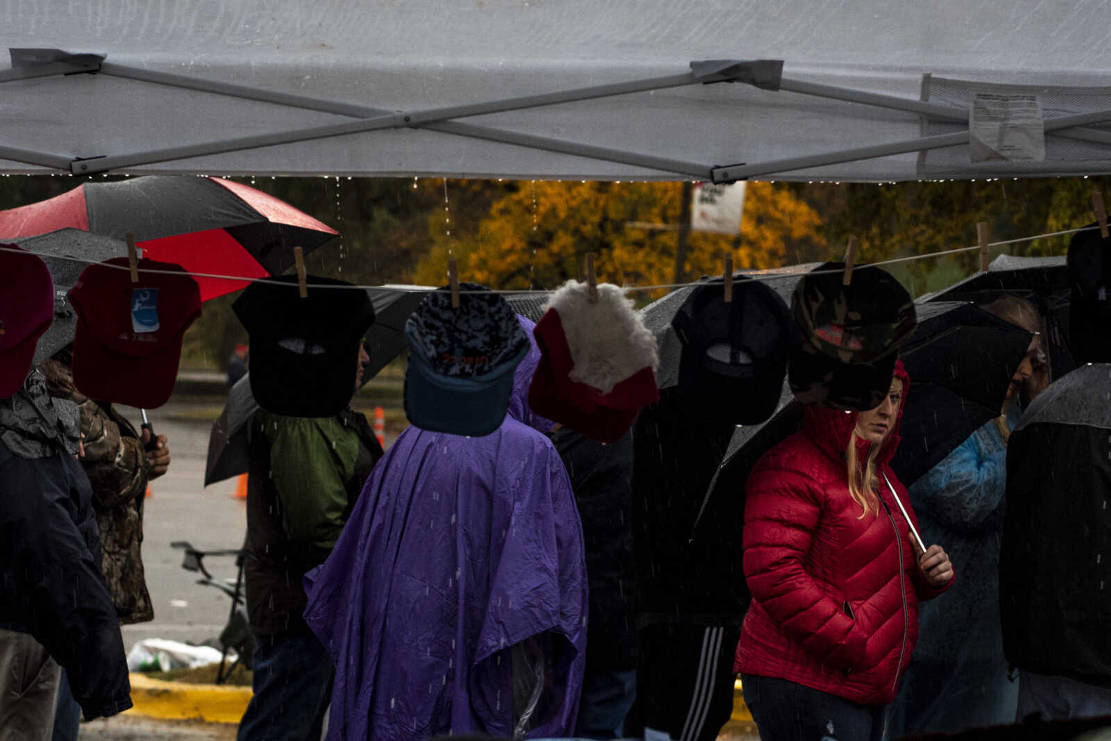 Supporters of President Trump stand in line in front of a vendor's tent as rain pours down outside of the Show Me Center Monday, Nov. 5, 2018, in Cape Girardeau.