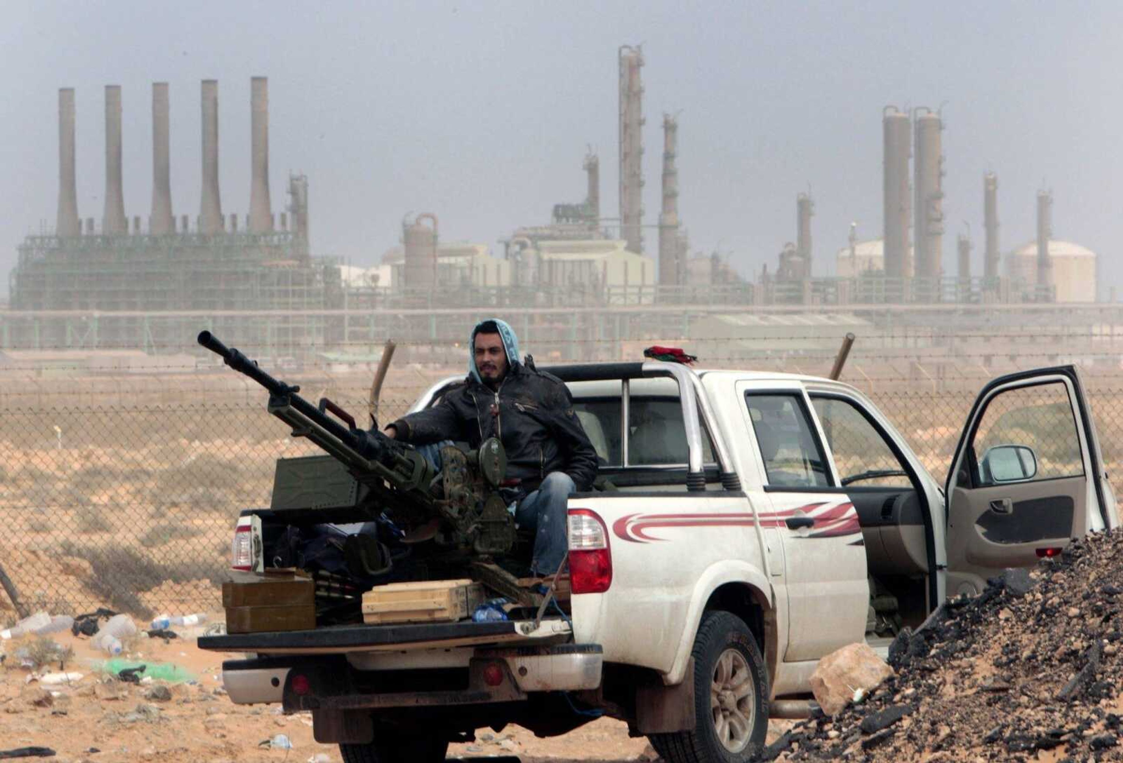 FILE - In this March 5, 2011 file photo, an anti-government rebel sits with an anti-aircraft weapon in front an oil refinery in Ras Lanouf, eastern Libya. The fight for Libya'Ã„Ã´s Ras Lanuf refinery and nearby Sidr depot threatens to spiral into open conflict between rival factions vying for power from east and west. With both sides claiming the facilities as their own but control unclear, decisive days lie ahead. (AP Photo/Hussein Malla, File)