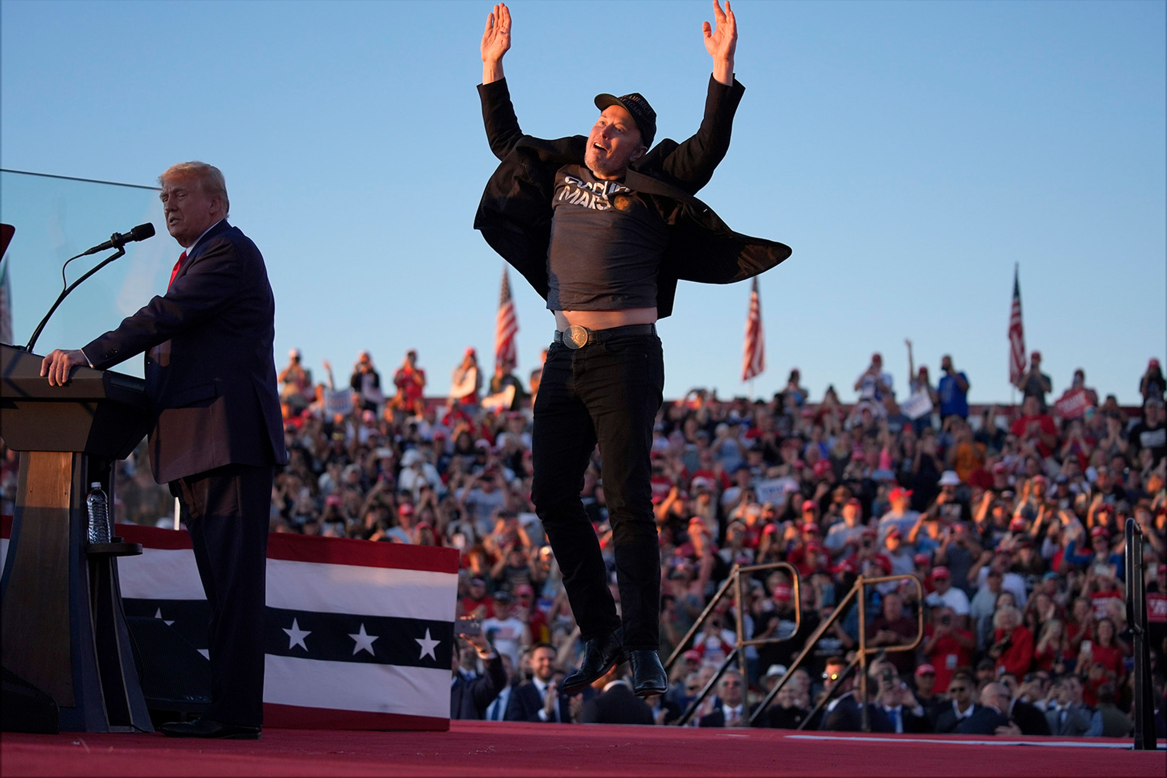 Elon Musk jumps on the stage as Republican presidential nominee former President Donald Trump speaks at a campaign rally at the Butler Farm Show, Saturday, Oct. 5, 2024, in Butler, Pa. 