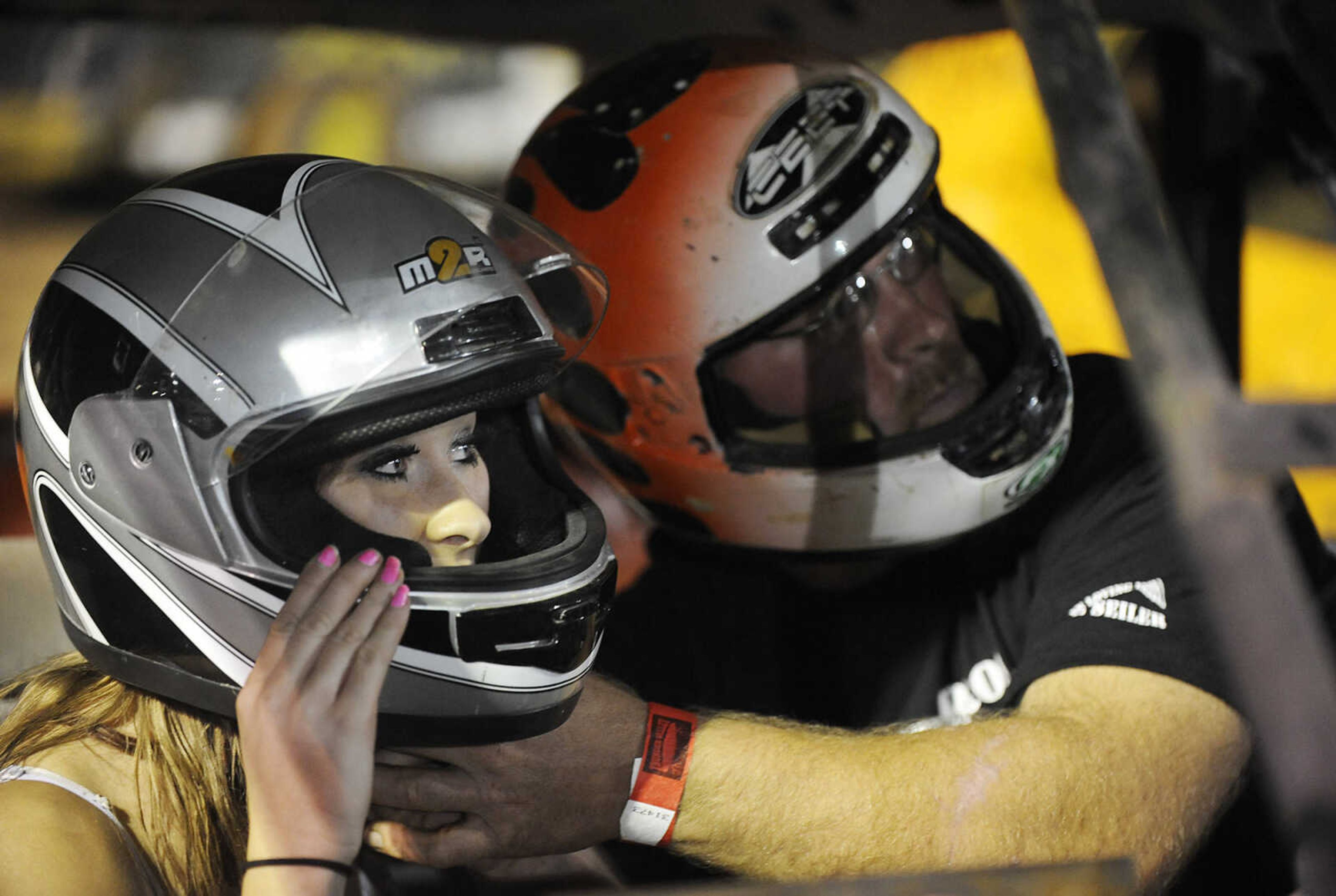 Mark Mayfield, right helps Leslie Welker with her helmet before they take to the track during the Dual Demo Derby at the SEMO District Fair Tuesday, September 11, at Arena Park in Cape Girardeau. Just seconds into thier heat Mayfield and Welker's car was disabled and Welker was injured.