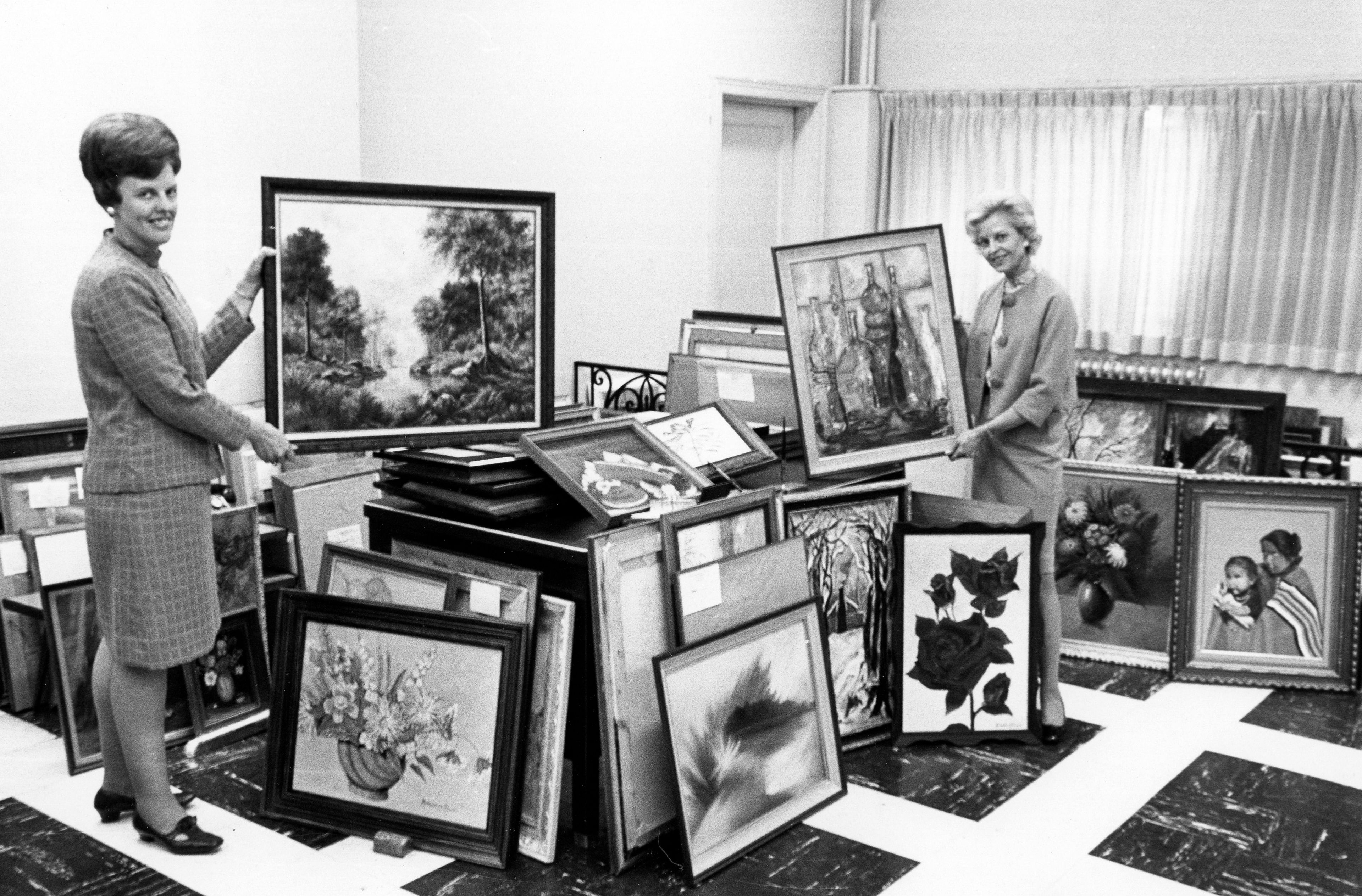 Amid stacks of paintings entered in the 23rd annual Missourian Art Exhibition on Nov. 22-23, 1969, Marjorie Suedekum, director, and Elizabeth Blackwell, assistant director, compare a landscape and a still life. Suedekum holds "Autumn Beauty" by Linda Burr of Bonne Terre and Blackwell holds "Glass Jewels" by Mrs. J. Griffey of Potosi.