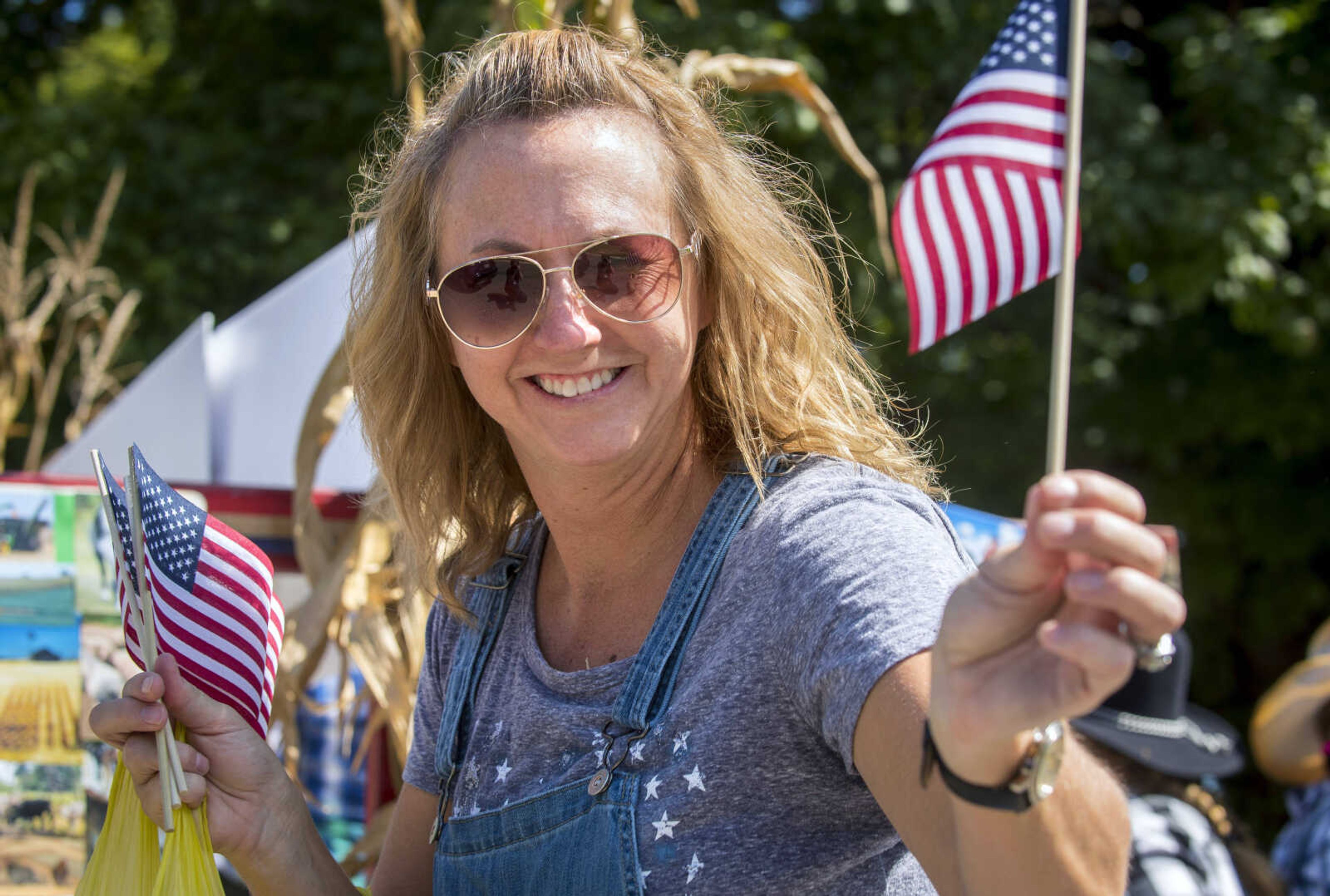 A parade walker passes out miniature American flags during Benton Neighbor Days Saturday, September 1, 2018.