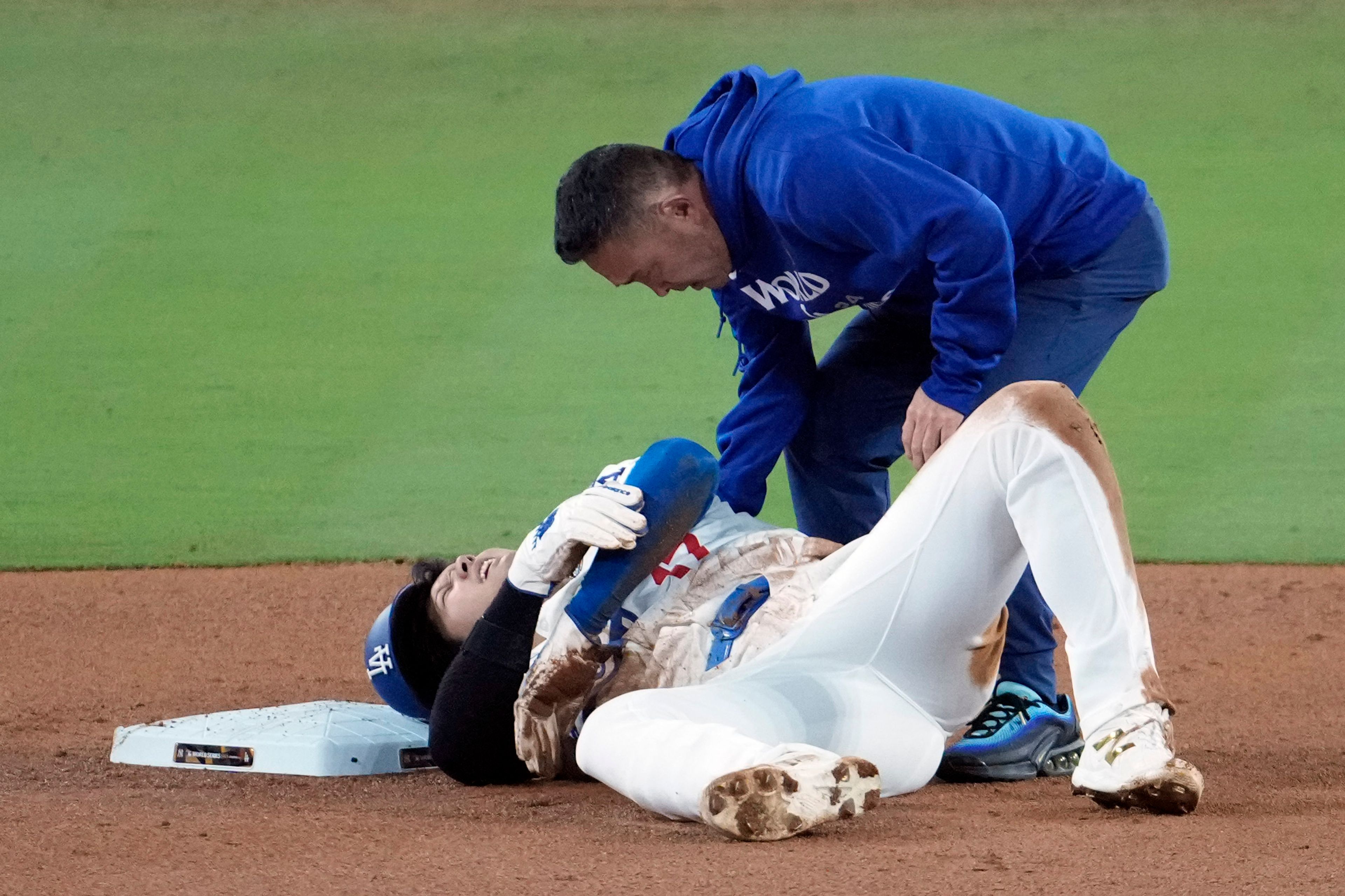 Los Angeles Dodgers' Shohei Ohtani lays on the ground after being injured while trying to steal second base against the New York Yankees during the seventh inning in Game 2 of the baseball World Series, Saturday, Oct. 26, 2024, in Los Angeles. (AP Photo/Julio Cortez)