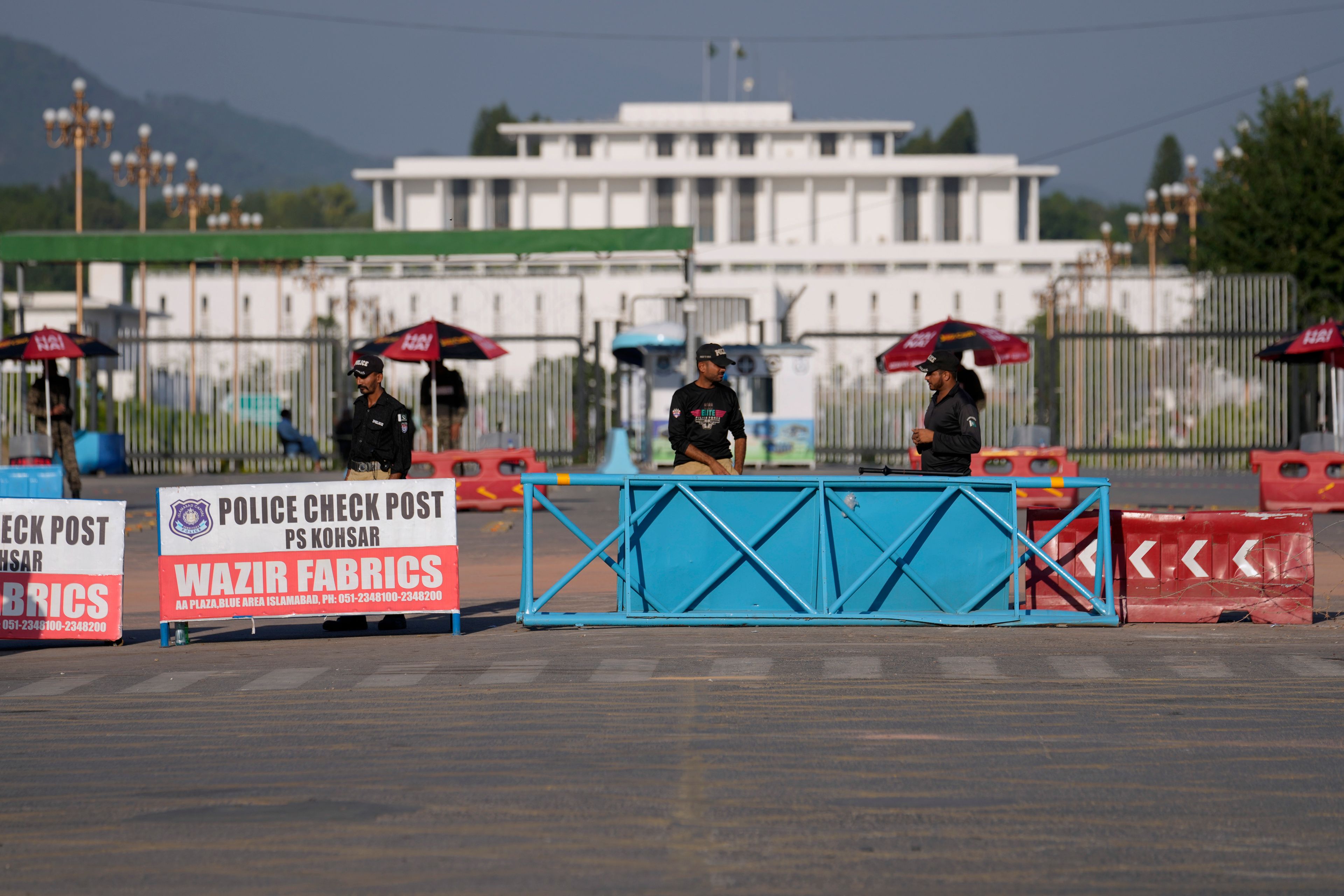 Police officers stand guard at a barricaded road leading to Presidency, in background, and to the venue of the upcoming Shanghai Cooperation Organization (SCO) summit in Islamabad, Pakistan, Sunday, Oct. 13, 2024. (AP Photo/Anjum Naveed)