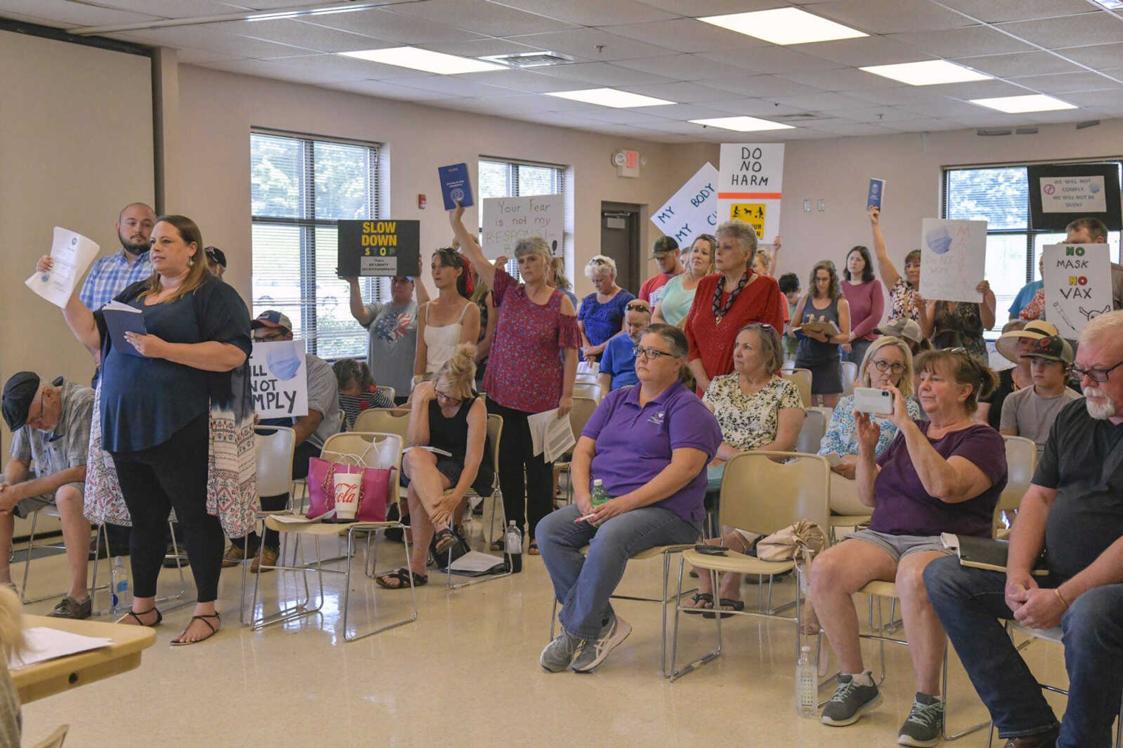 Audience members stand as one of them speaks and holds up a copy of the board’s oath of office during a Cape Girardeau County Public Health Center board meeting Tuesday at Shawnee Park Center in Cape Girardeau. 