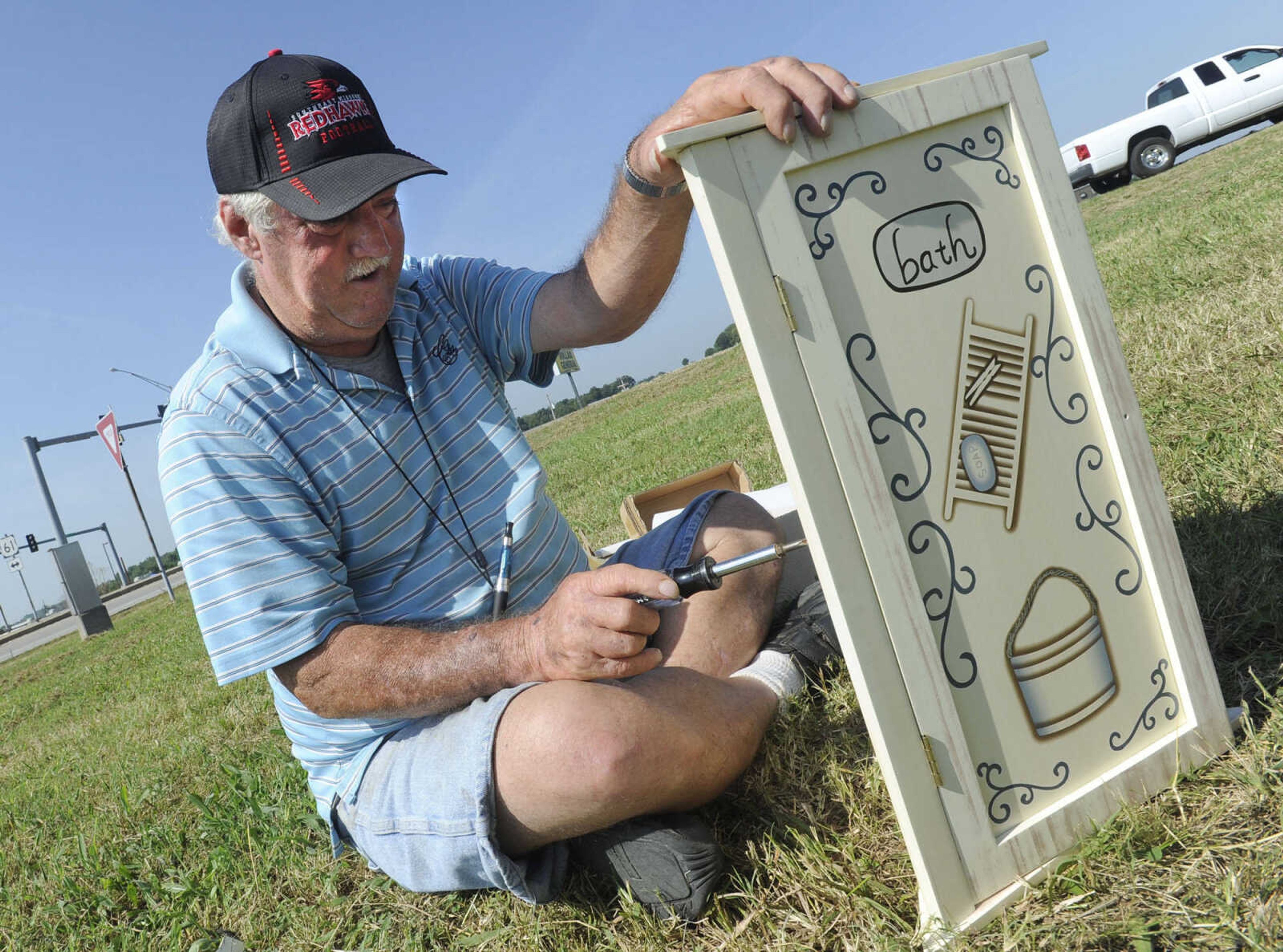 Kenny Wallace of Cape Girardeau assembles a bathroom corner cabinet to offer for sale at his stand during the Highway 61 Yard Sale Saturday, Aug. 31, 2013 in Fruitland.