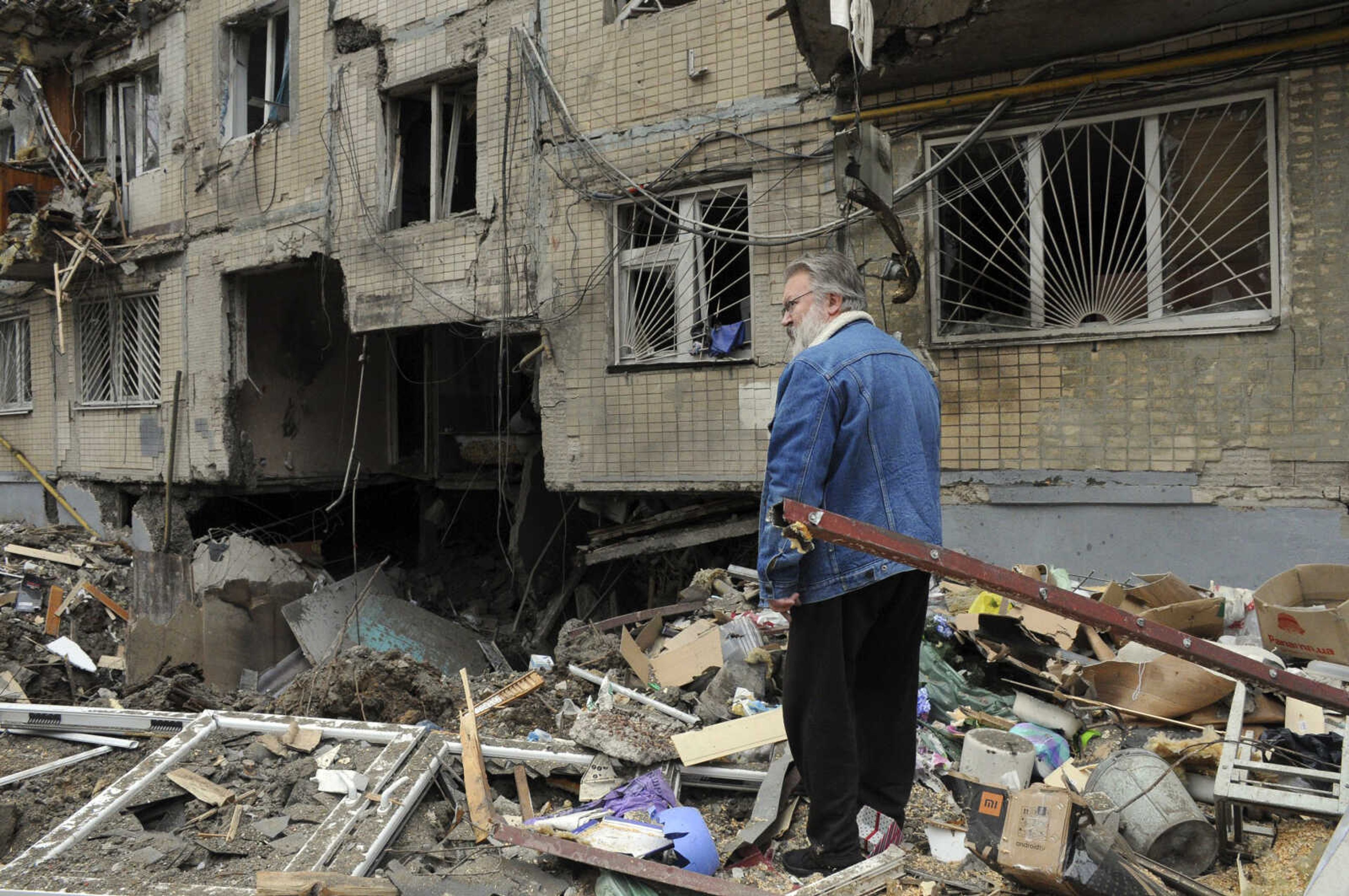 A man stands next to an apartment building damaged by shelling, Sunday in Kharkiv, Ukraine.