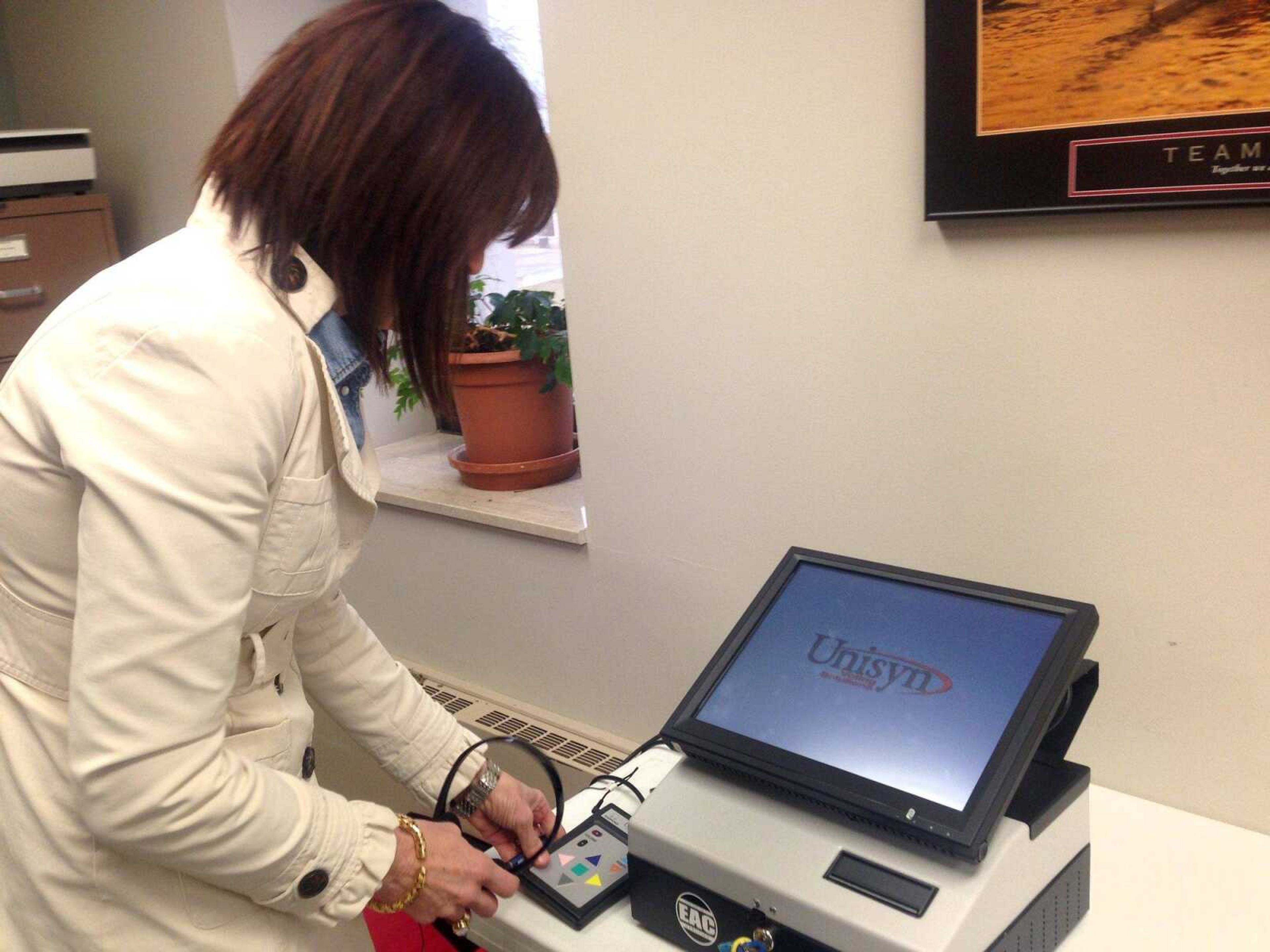 Cape Girardeau County Clerk Kara Clark Summers boots up an OVI Accessible Voting Unit on Thursday. The large screen, keypad and headphones are designed to help vision-impaired voters cast ballots more easily. (Samantha Rinehart)