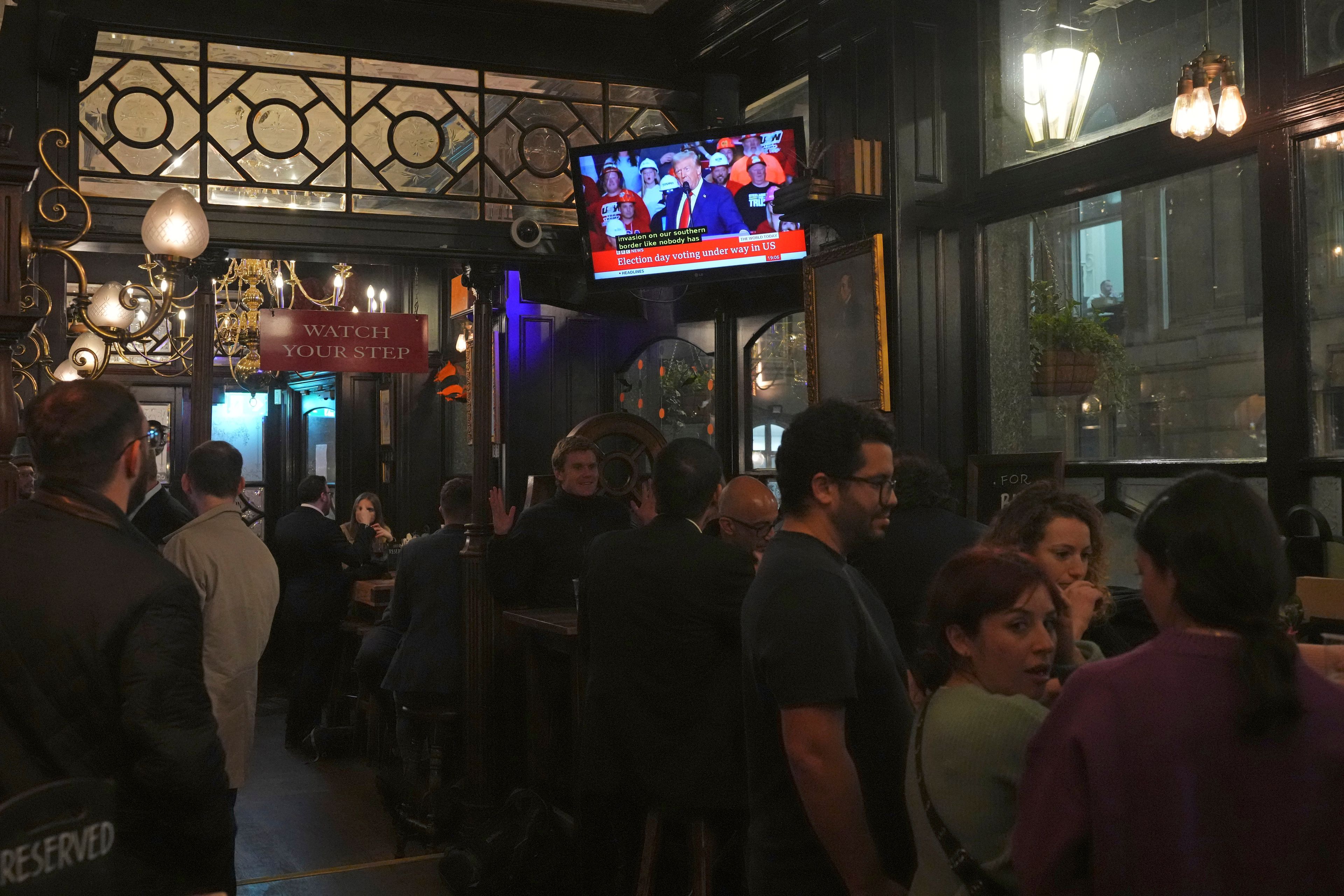 People in a London pub follow the news on TV screens about the U.S. election, Tuesday, Nov. 5, 2024. (AP Photo/Frank Augstein)