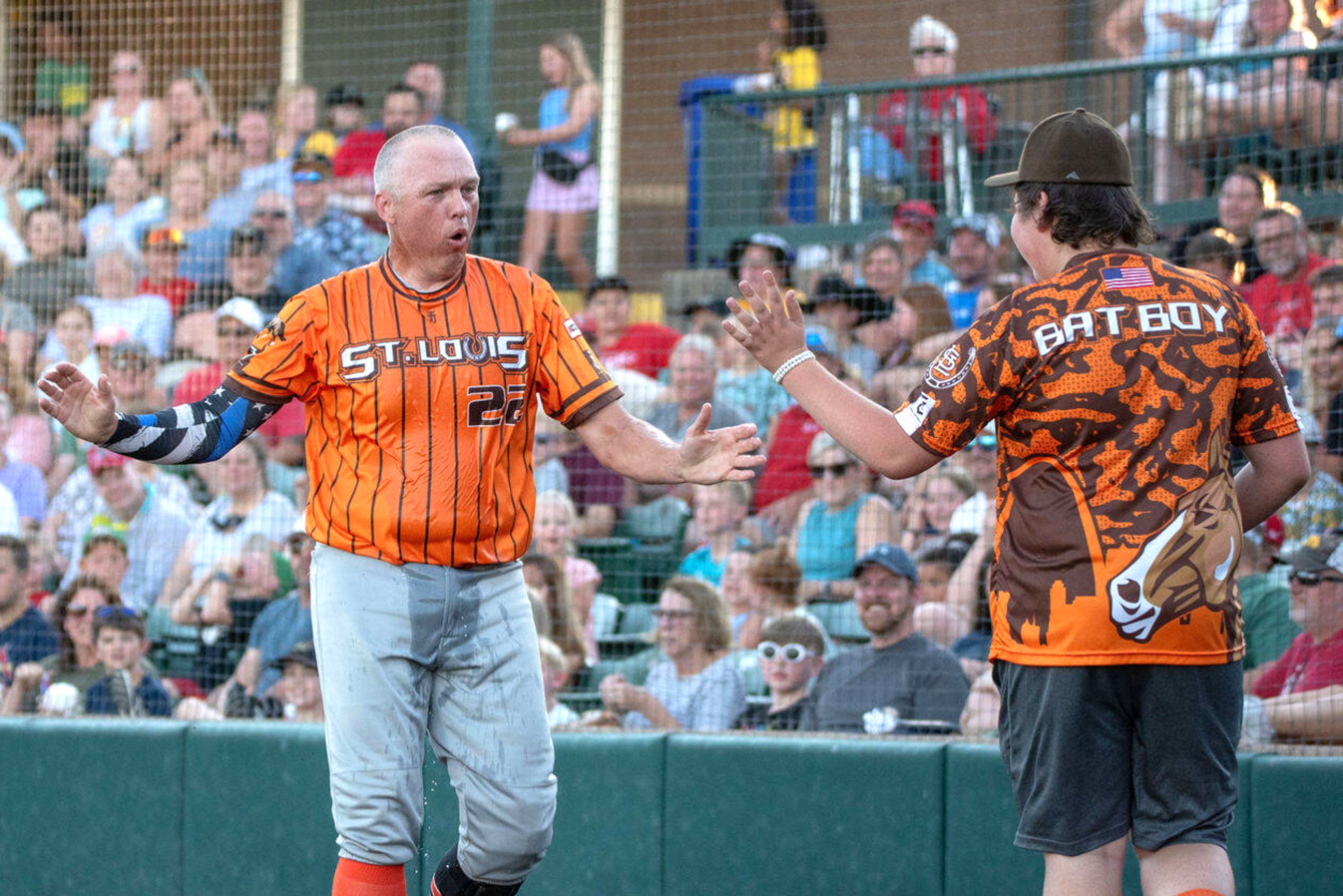 St. Louis Clydesdales co-founder and St. Peter’s Police Department patrolman John Aebischer goes to slap hands with a bat boy after dousing himself with water during the team’s “Hootenanny” exhibition at CarShield Field in O’Fallon.