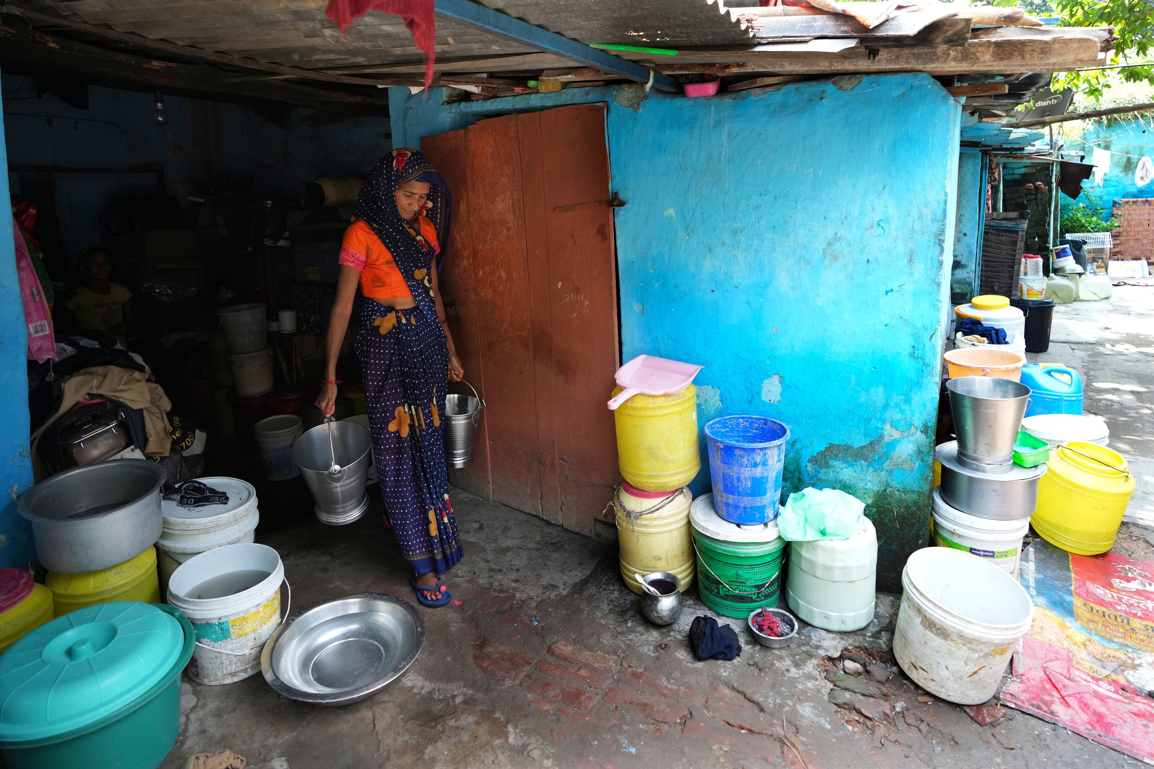 A woman carries Tata steel buckets for filling water in a shanty area, in Prayagraj, India, Thursday, Oct. 10, 2024. (AP Photo/Rajesh Kumar Singh)