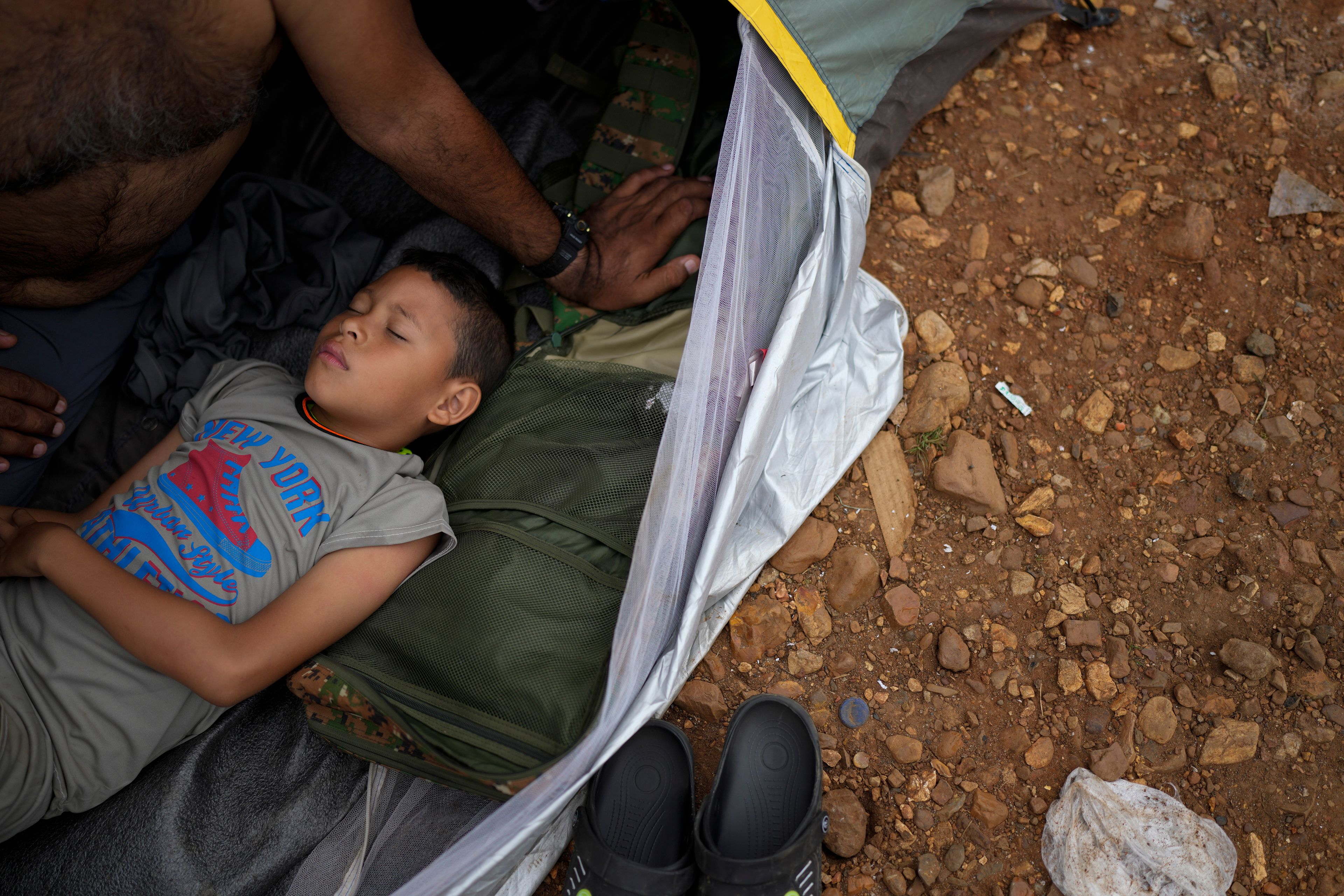 Emanuel Dordis, of Venezuela, sleeps next to his father at a camp for migrants who trekked across the Darien Gap in the hope of reaching the U.S., in Lajas Blancas, Panama, Thursday, Sept. 26, 2024. (AP Photo/Matias Delacroix)