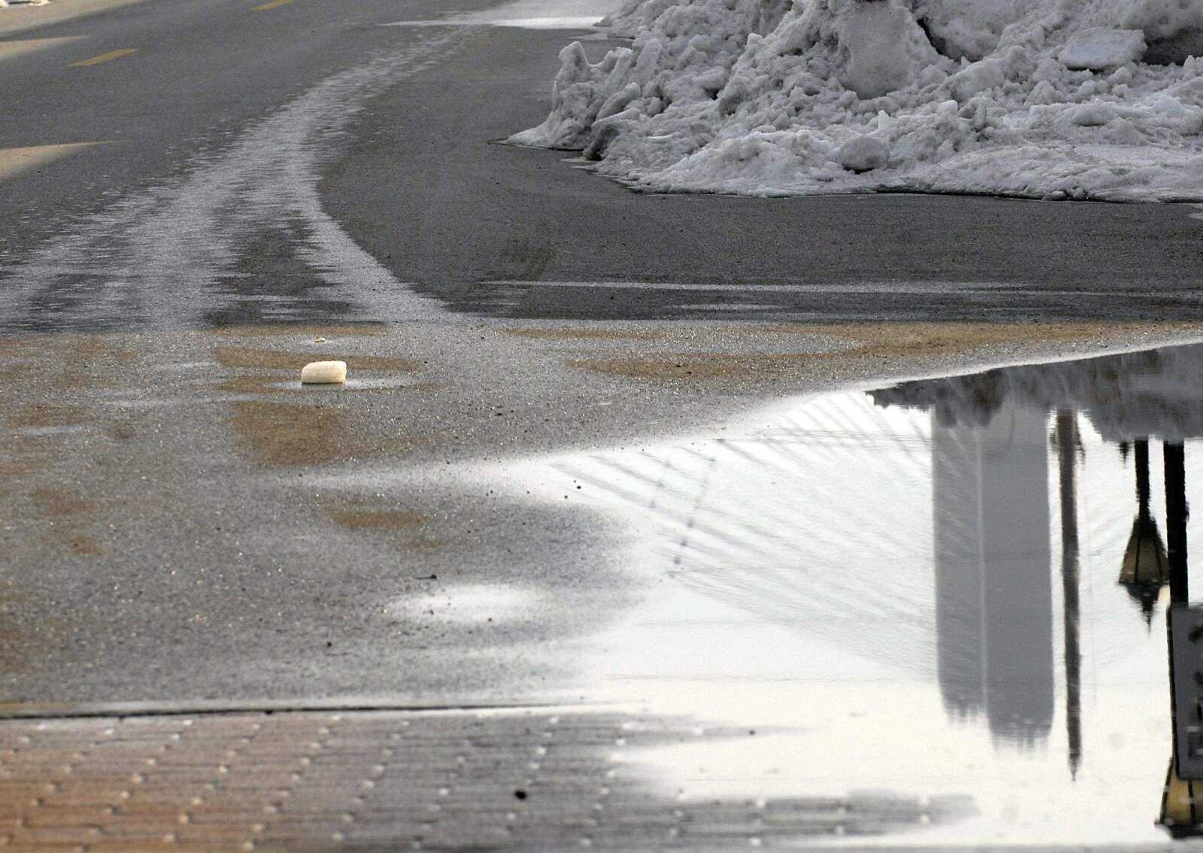 ELIZABETH DODD ~ edodd@semissourian.com
Puddles form from the melting snow reflecting the Emerson Bridge on Main Street.