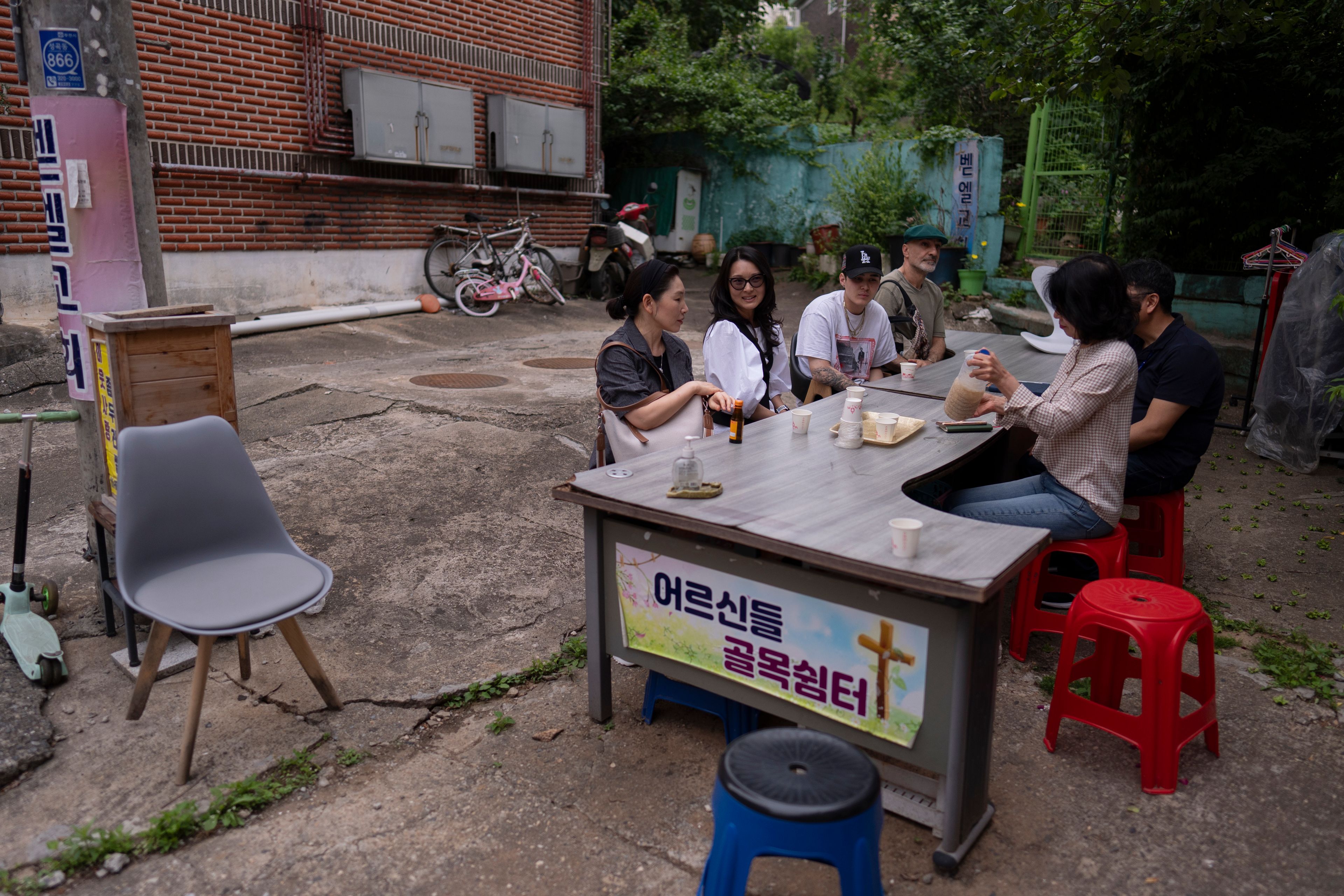 Nicole Motta, second from left, an adoptee visiting from Los Angeles, chats with Paek Kyeong-mi from Global Overseas Adoptees' Link, during a break from searching for Motta's birth family in Bucheon, South Korea, Thursday, May 30, 2024. (AP Photo/Jae C. Hong)