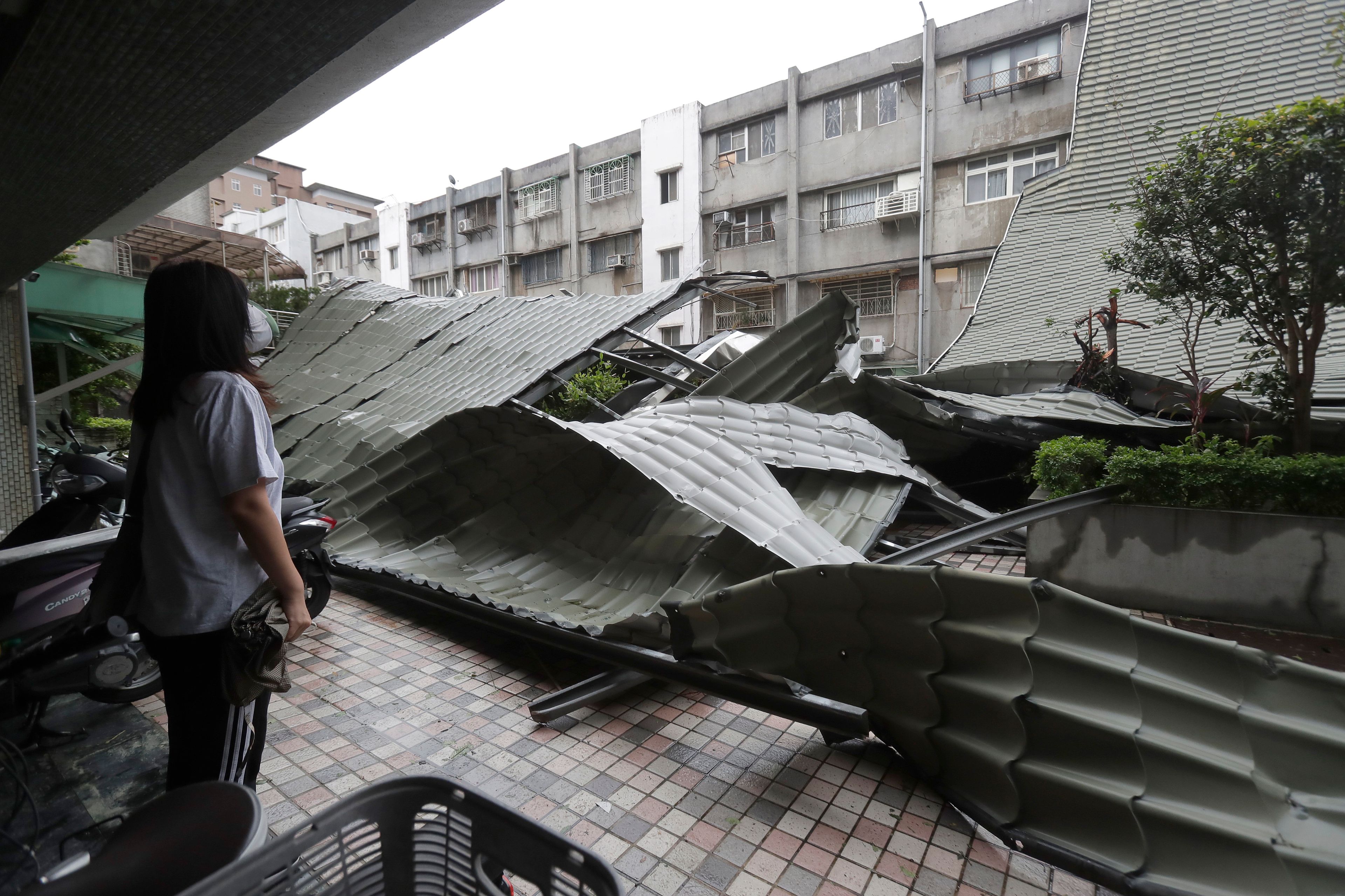 A woman looks at a row of blown roofs destroyed by the wind of Typhoon Kong-rey in Taipei, Taiwan, Friday, Nov. 1, 2024. (AP Photo/Chiang Ying-ying)