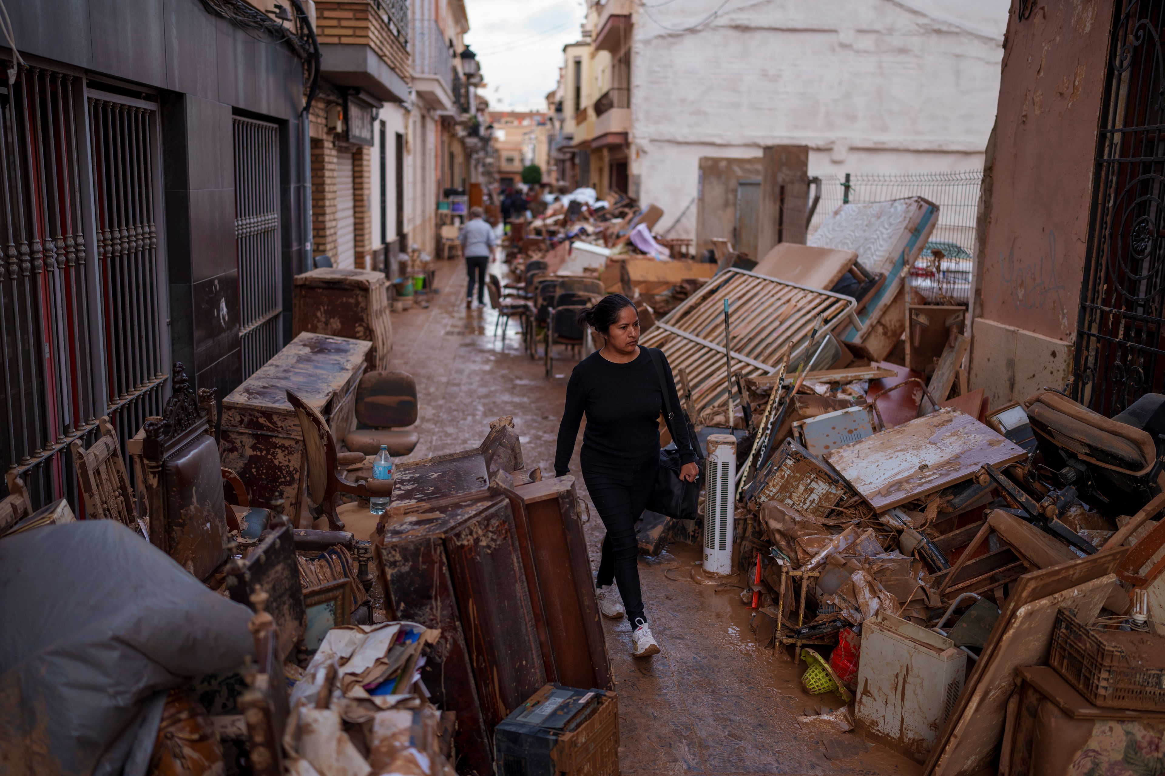 A woman walks through the street in an area affected by floods in Sedavi, Spain, Friday, Nov. 1, 2024. (AP Photo/Manu Fernandez)