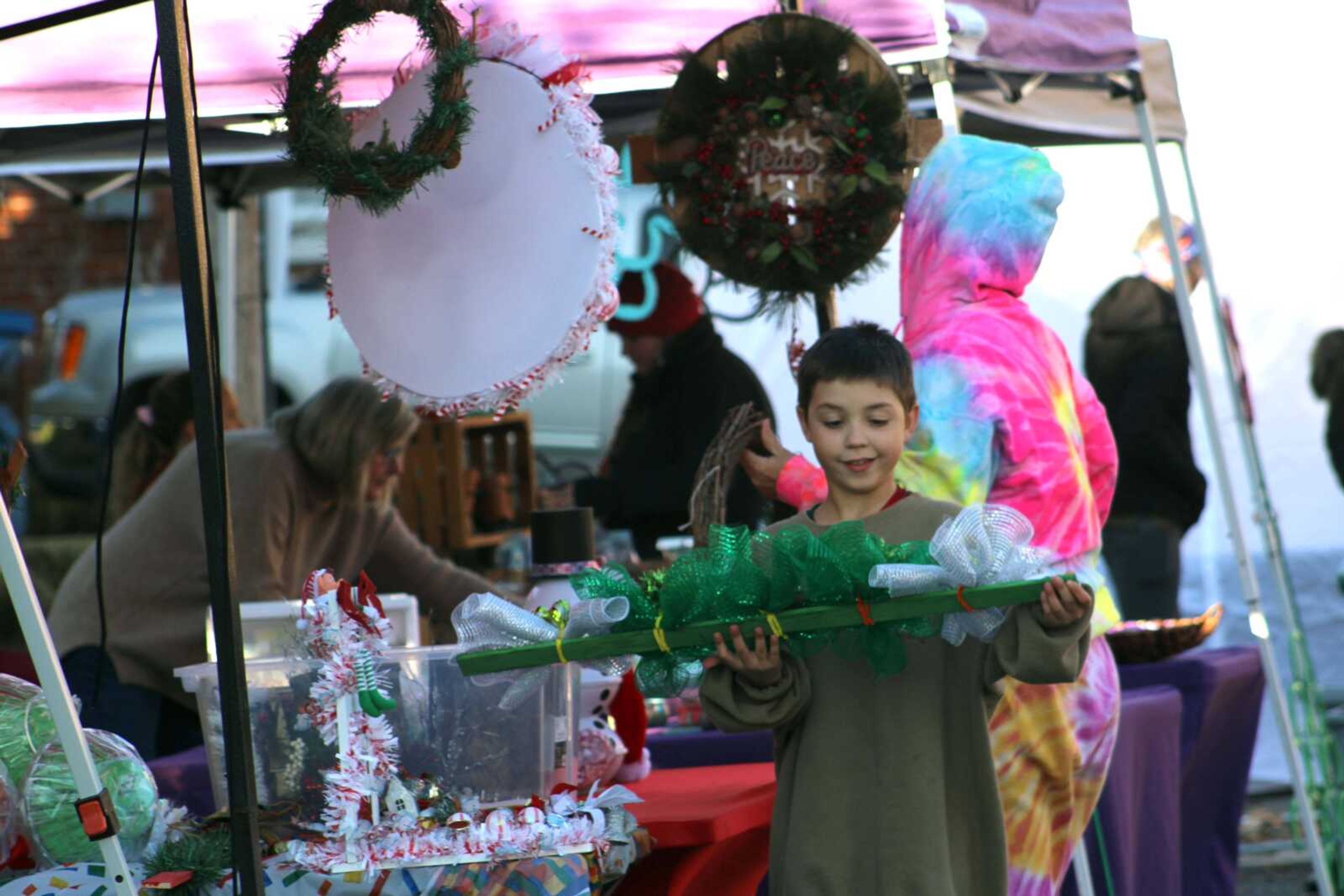 A young boy looks at a holiday wreath available for purchase during the third annual Old Town Cape, Inc. Holiday Bazaar Saturday, Dec. 5, 2021, on Frederick Street in downtown Cape Girardeau.