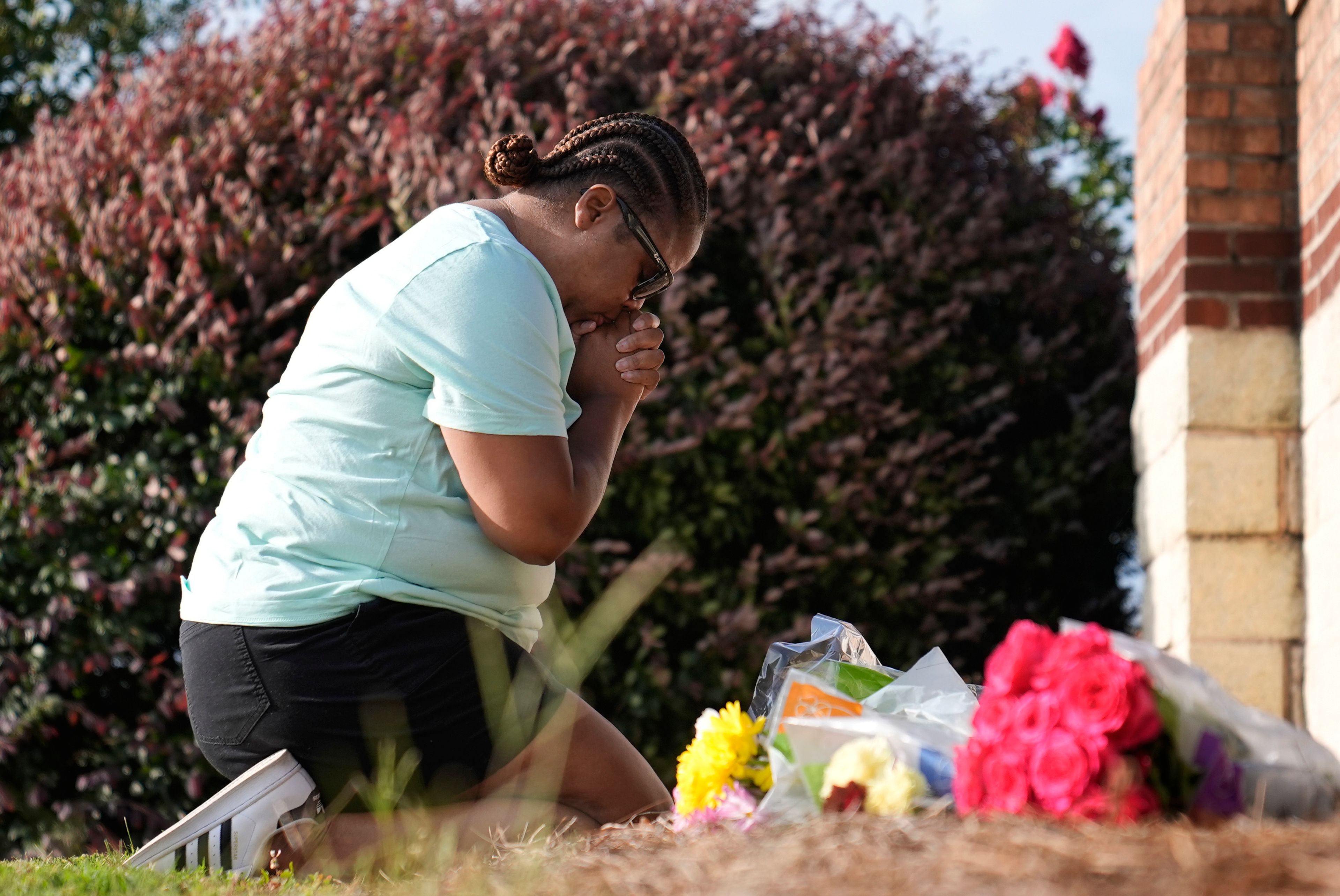 Linda Carter, of Grayson, Ga., kneels near Apalachee High School to place flowers as she mourns for the slain students and teachers on Thursday, Sept. 5, 2024, in Winder, Ga. (AP Photo/Brynn Anderson)