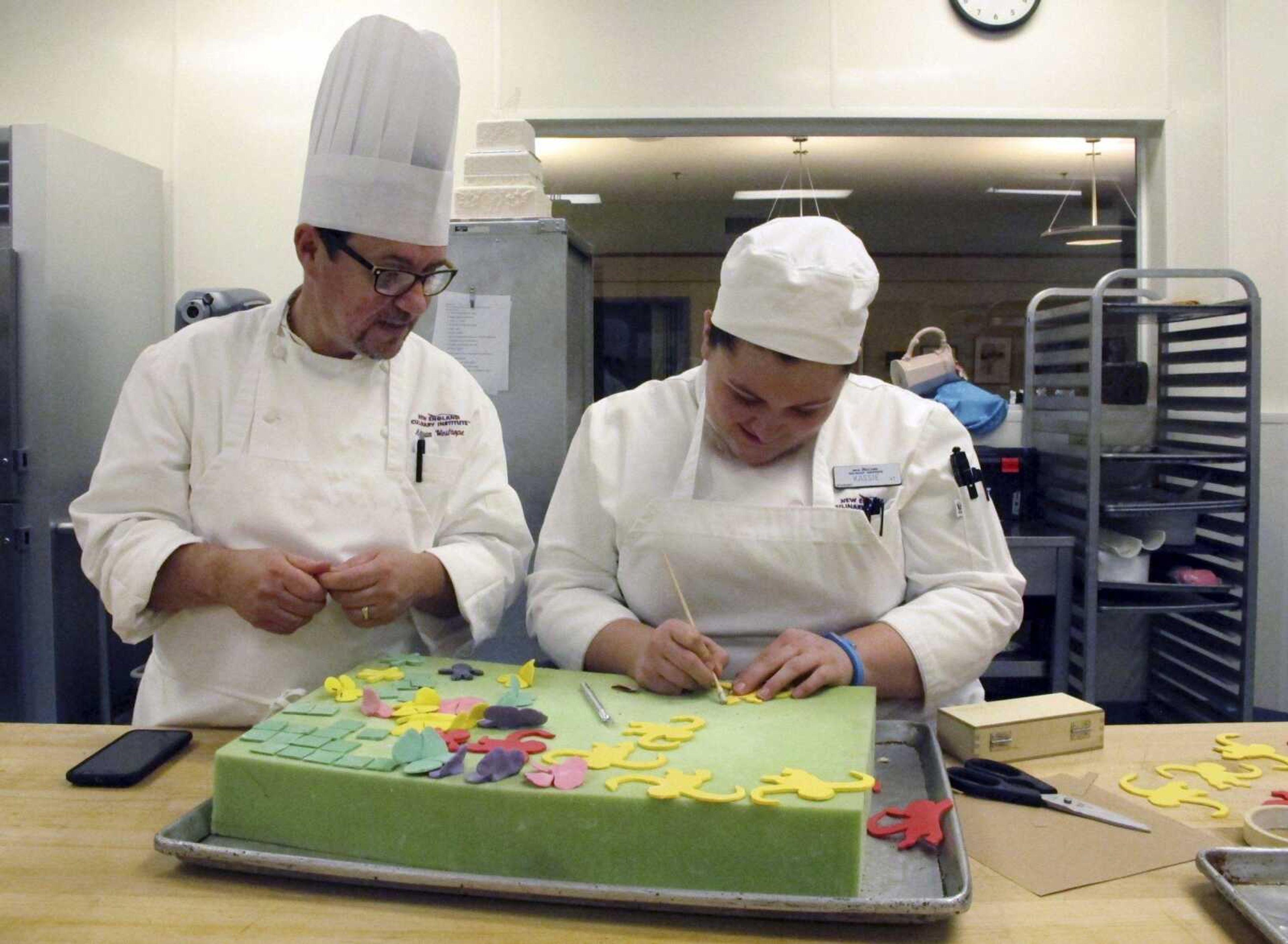 New England Culinary Institute instructor Chef Adrian Westrope, left, discusses a dessert project Thursday with student Kassie Jardine in Montpelier, Vermont. Enrollment in culinary institutes across the country is in decline, and some cooking schools have announced they are closing.