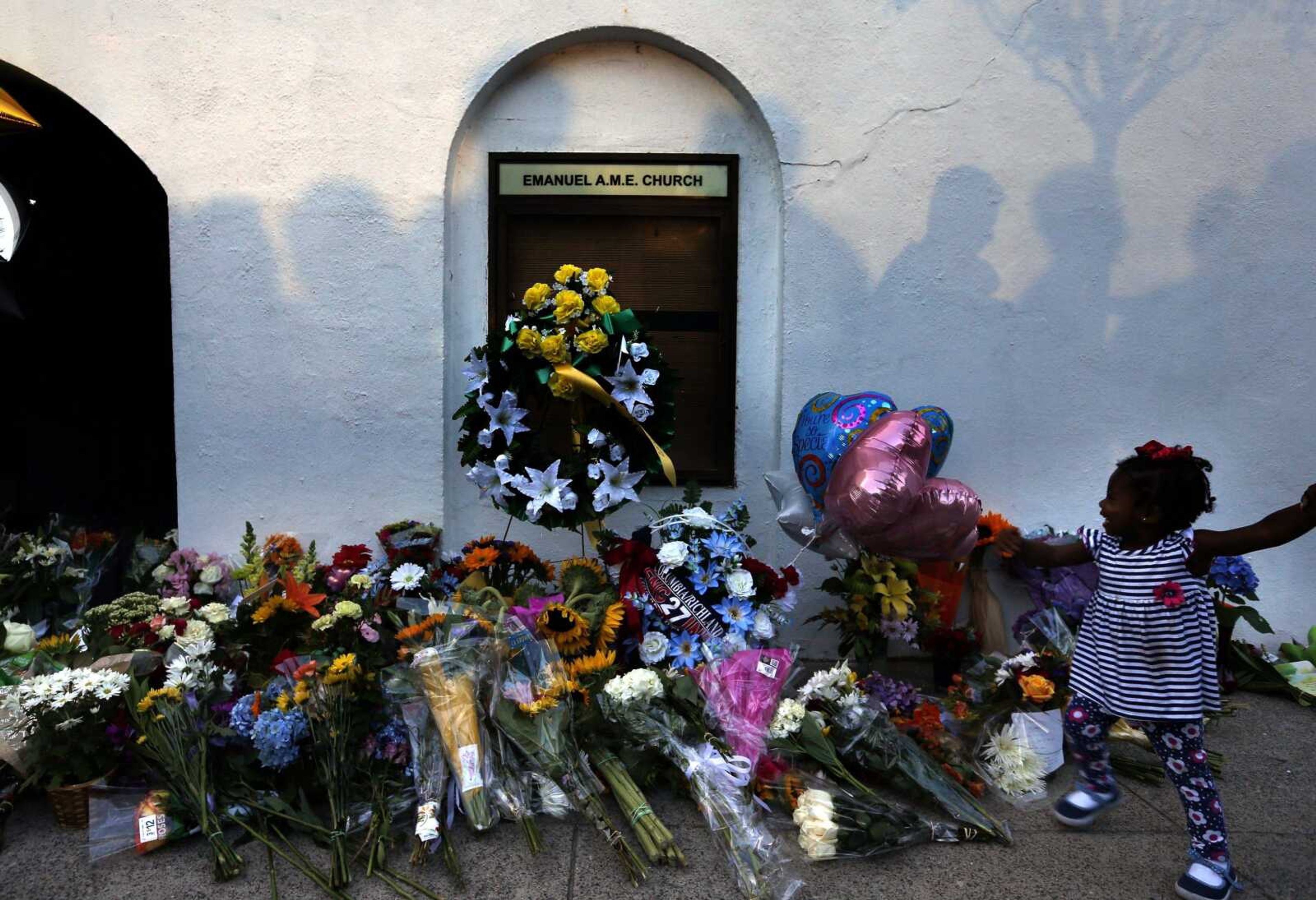 Mourners pass by a makeshift memorial June 18, 2015, on the sidewalk in front of the Emanuel AME Church after a mass shooting by Dylann Roof in Charleston, South Carolina.