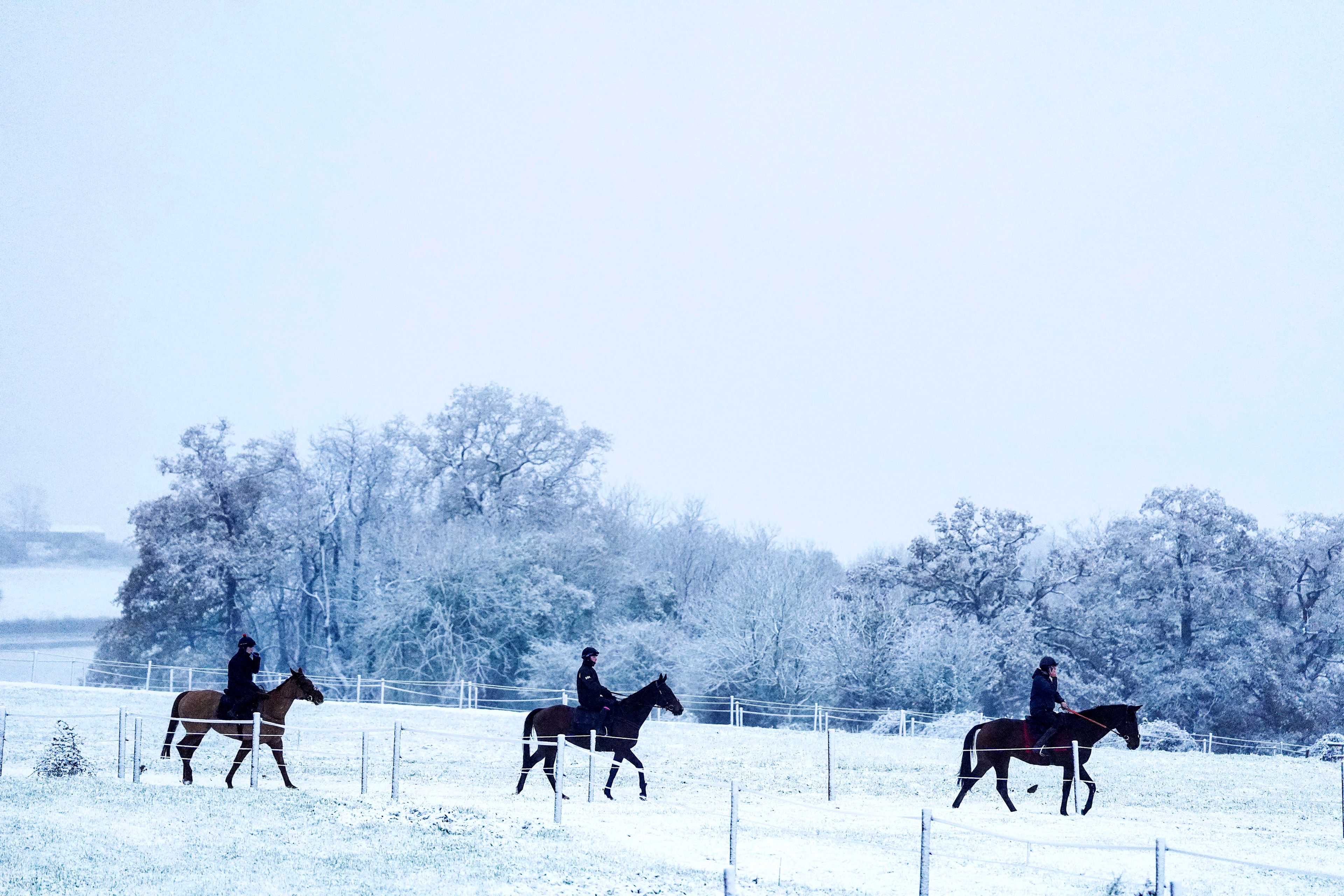 People ride horses after a snowfall at Sam Drinkwater's Granary Stables, Strensham, England, Tuesday, Nov. 19, 2024. (David Davies/PA via AP)