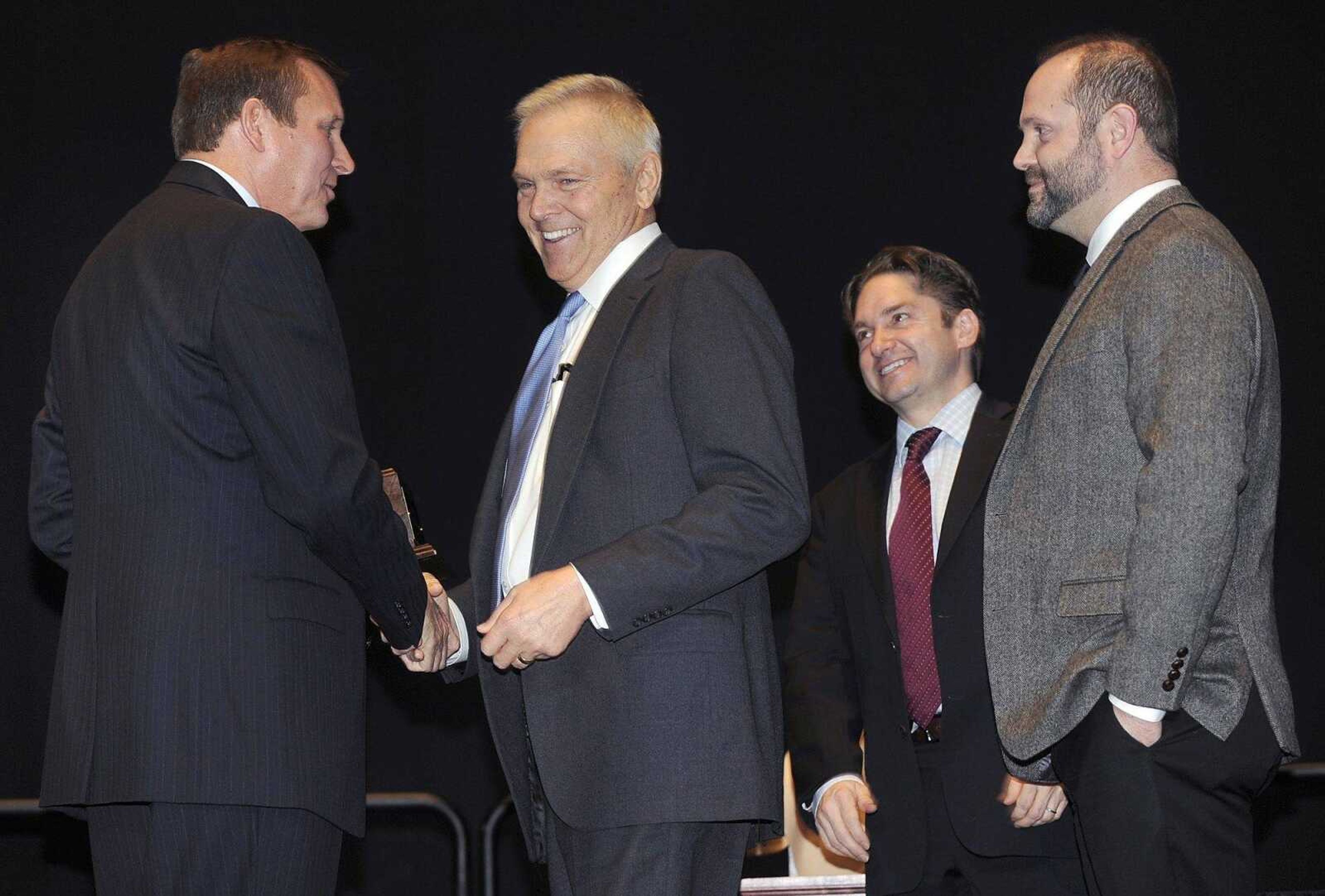 Bob Neff, left, outgoing chairman of the Cape Girardeau Area Chamber of Commerce, presents a Small Business of the Year Award to Michael Bennett and Ross Bennett, right, of Bennett Family Dentistry, as incoming chamber chairman Jon K. Rust looks on at its annual dinner Friday at the Show Me Center.