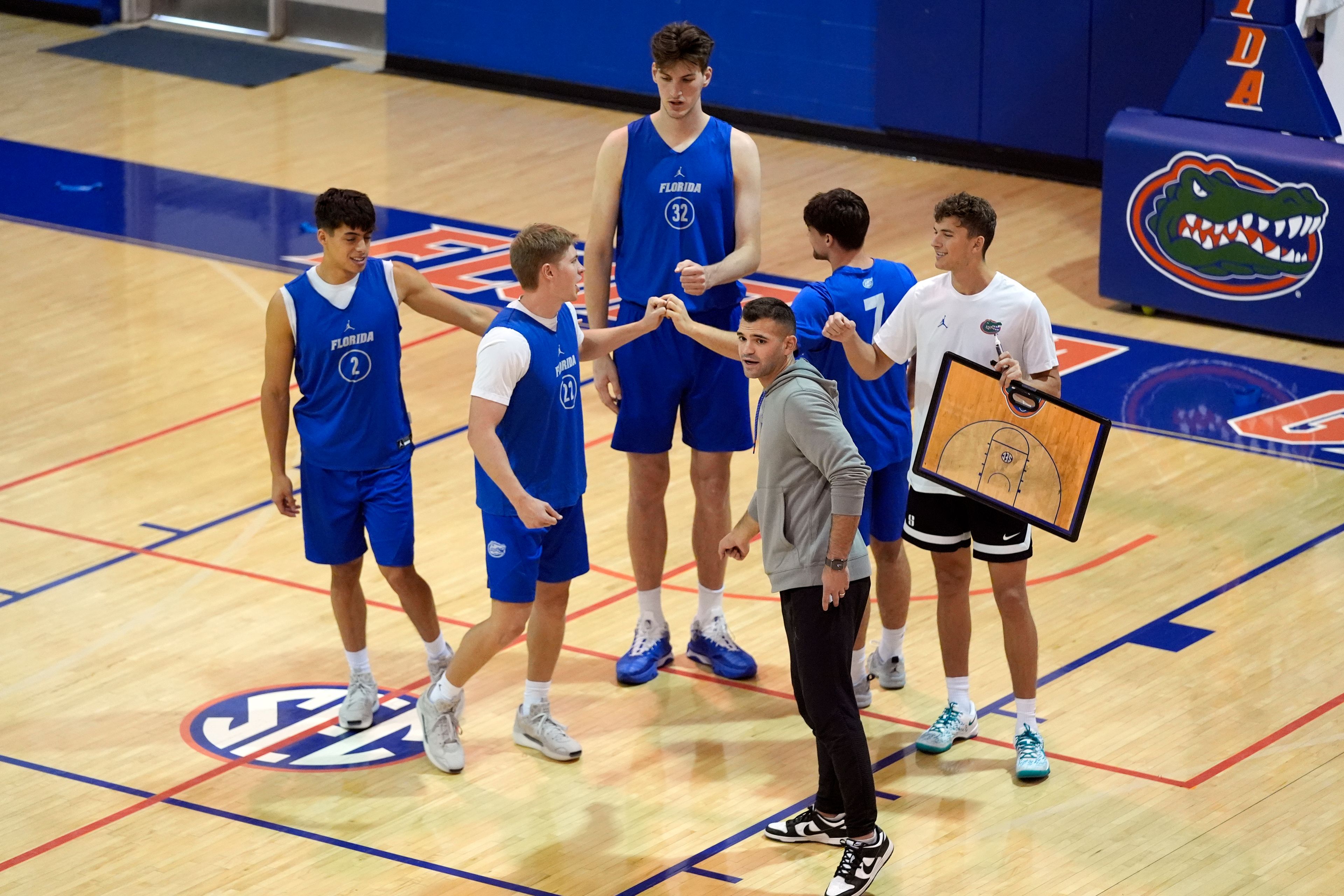 Olivier Rioux, back center, a 7-foot-9 NCAA college basketball player at Florida, gathers with coaches and teammates at the team's practice, Friday, Oct. 18, 2024, in Gainesville, Fla. (AP Photo/John Raoux)