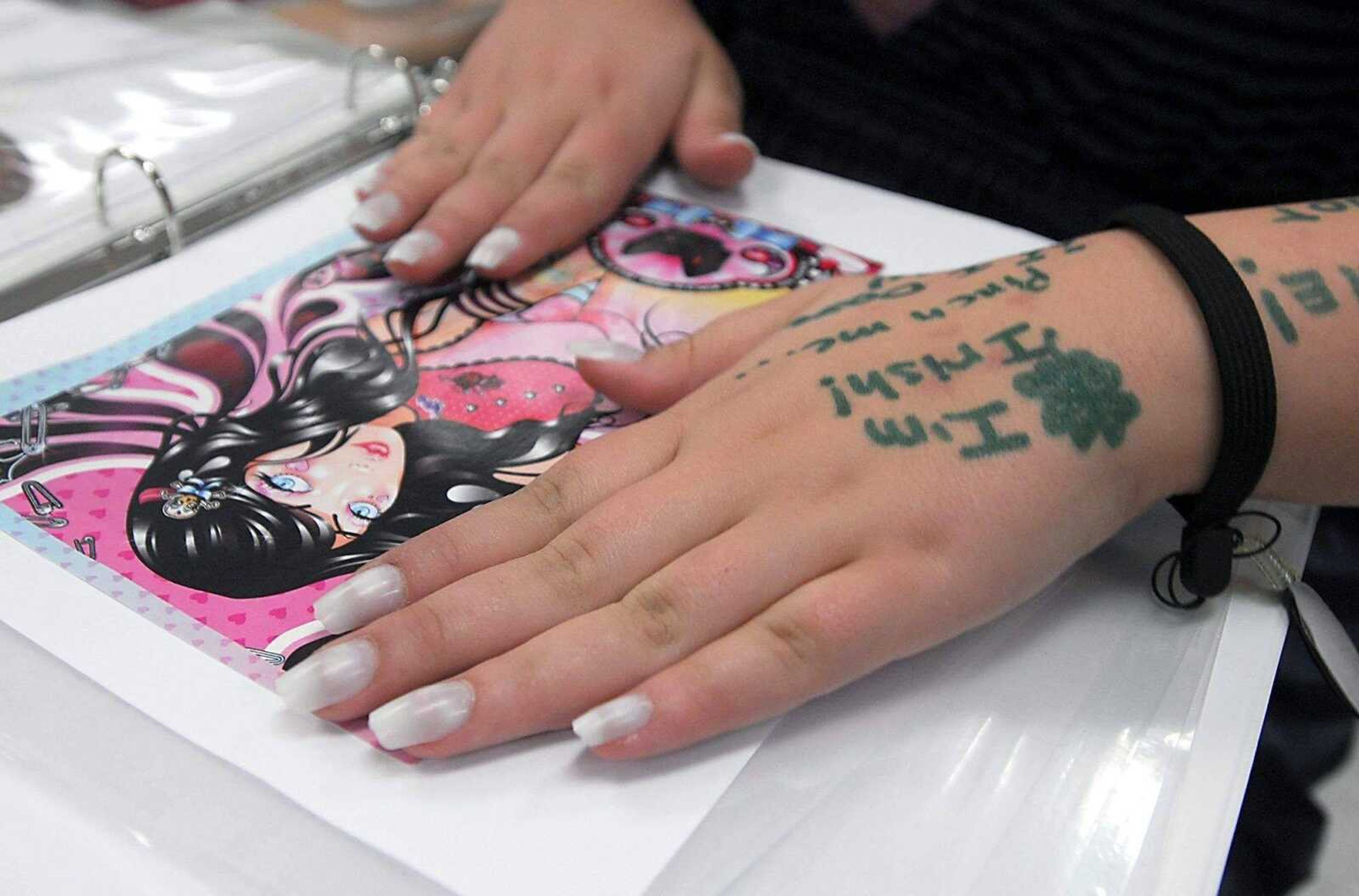 Fifteen-year-old Jessica Mercado holds down a freshly glued page for her memory book March 17 at Jackson Junior High. Students individualy chose images to use in memory books that will be distributed to area nursing homes.