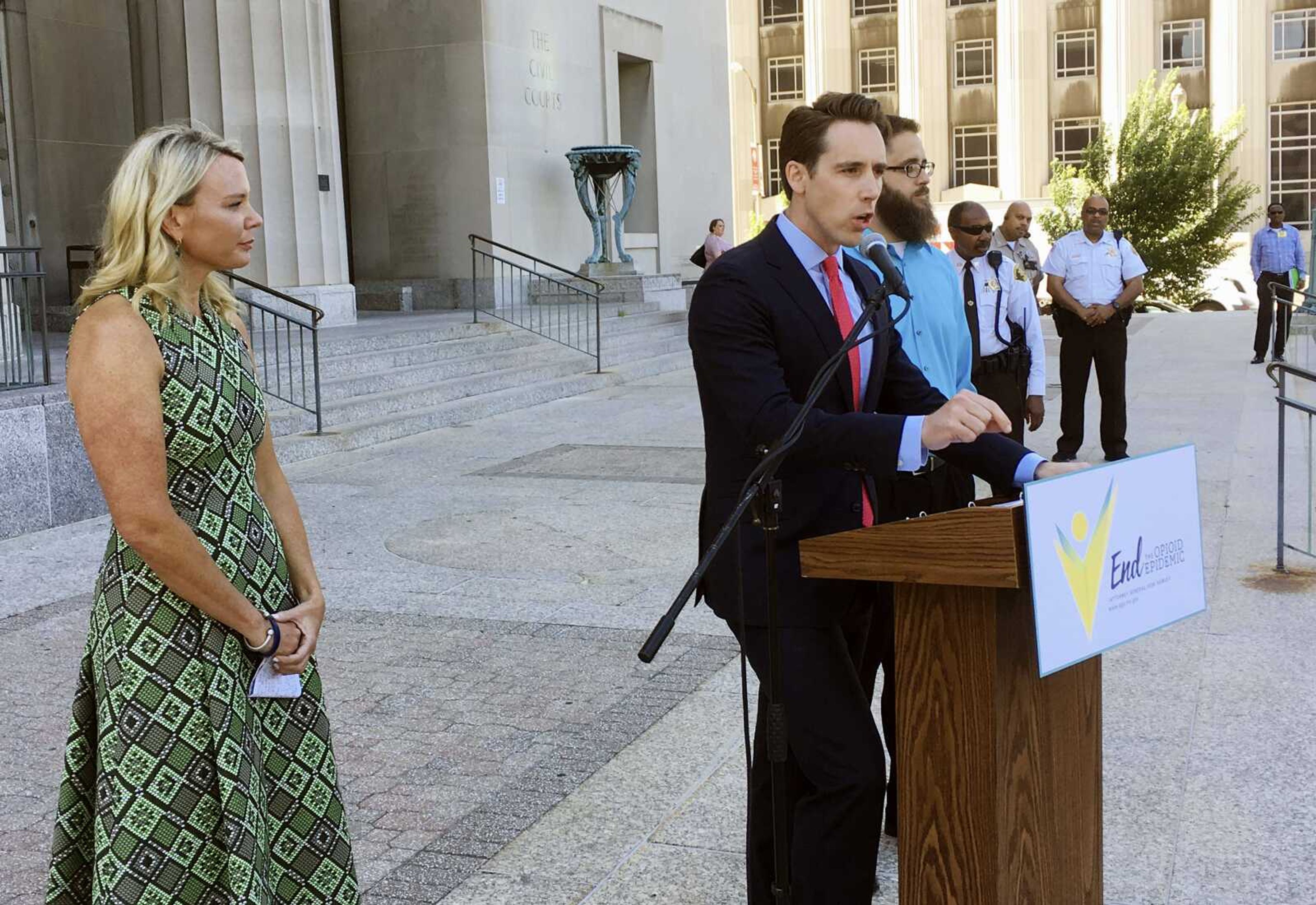 Missouri Attorney General Josh Hawley speaks at a news conference Wednesday in St. Louis, where announced he is suing three large pharmaceutical companies, saying their deceptive marketing practices contributed to an opioid abuse crisis in the state. Looking on at left is Jammie Fabick, whose 17-year-old daughter died of an opioid overdose in 2014.