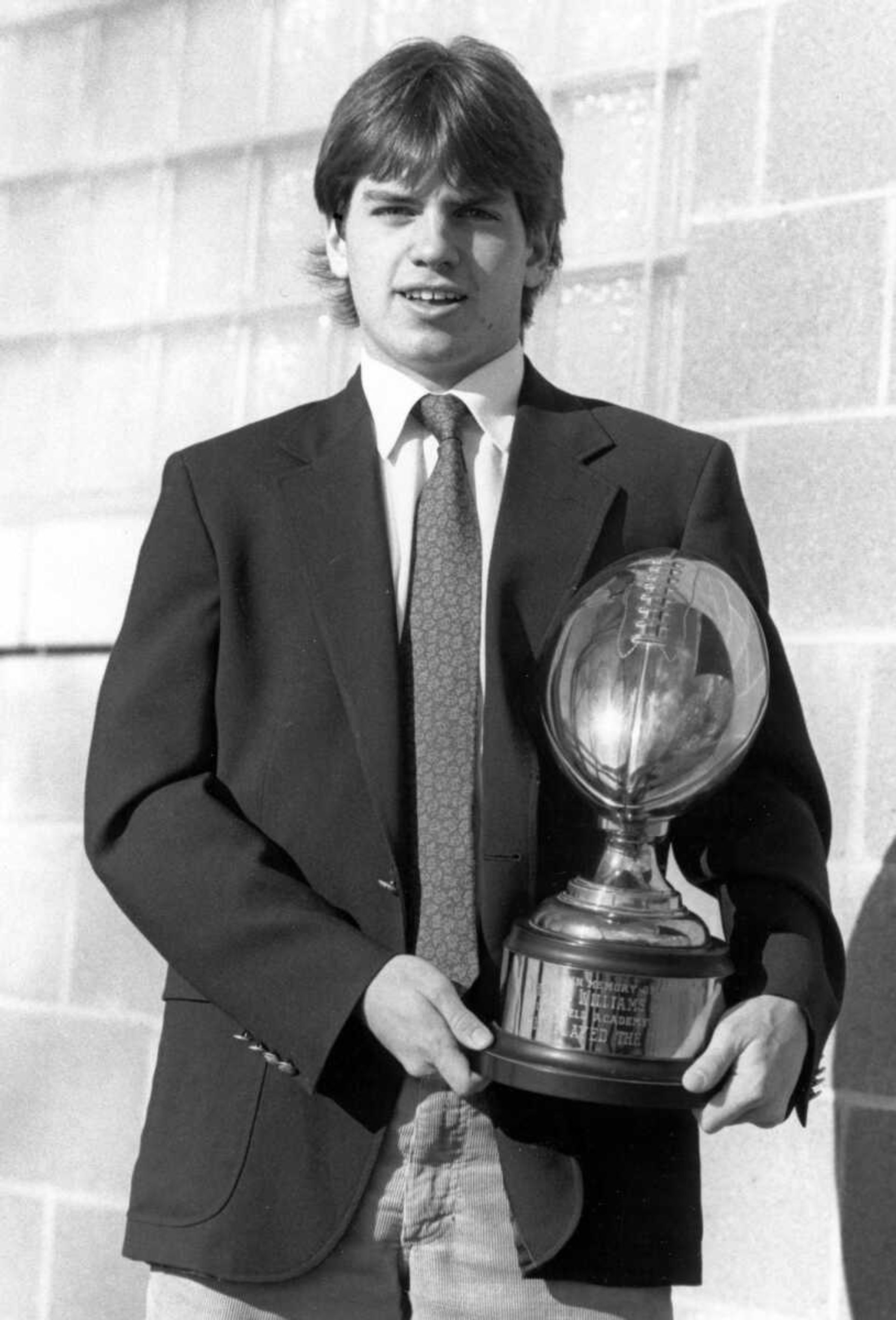 Rex Rust of Cape Girardeau stands with the Tom Ashley Award he won for being named the top football player at Deerfield (Massachusetts) Academy in 1987. Rust, a two-way starter, scored nine touchdowns for the 7-3 team. He is captain of the football, basketball and baseball teams at Deerfield Academy. The Tom Ashley Award is named after a former Deerfield standout.